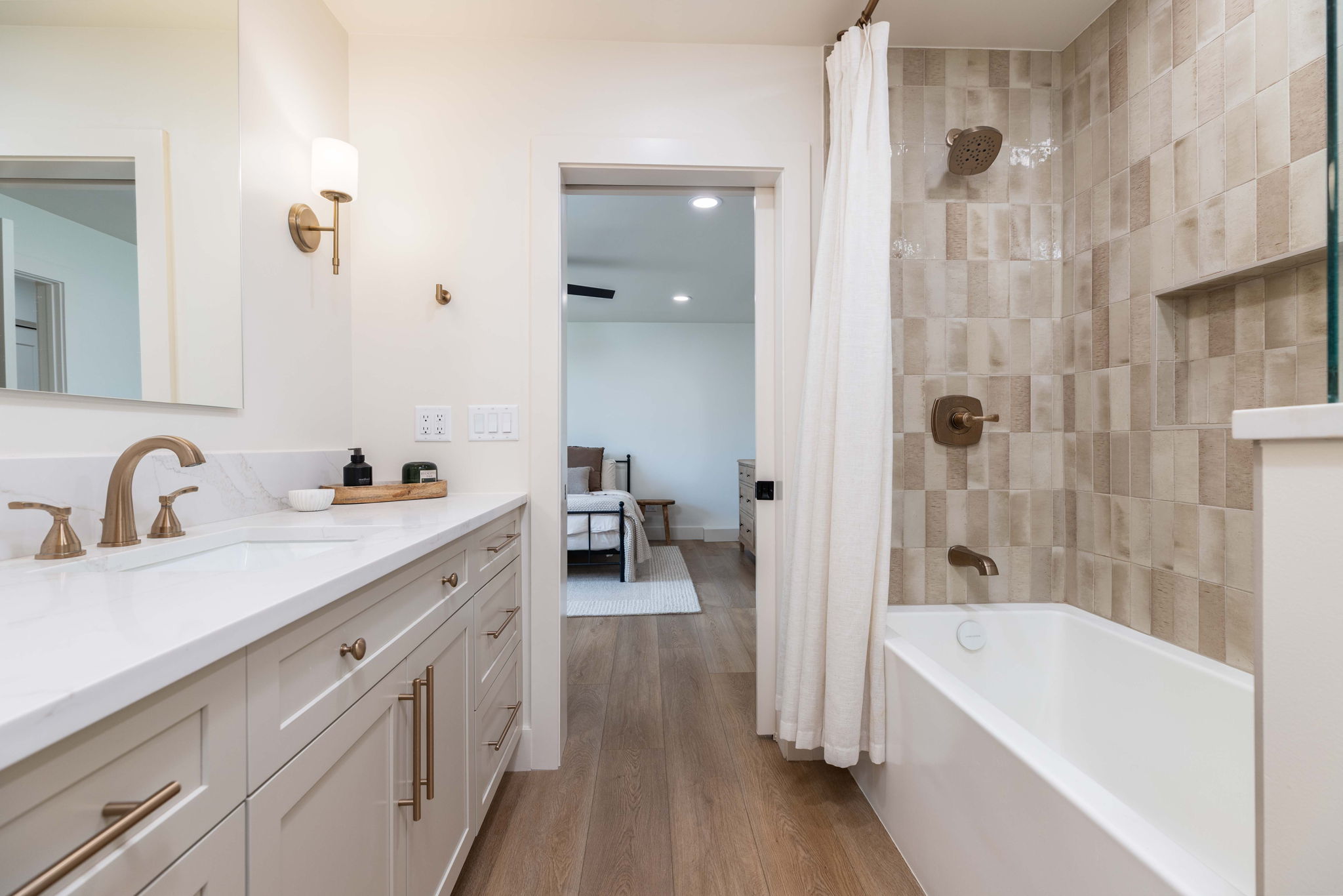 Bathroom featuring a long single vanity with a white countertop and undermount sink, brushed gold fixtures, and light-toned cabinetry