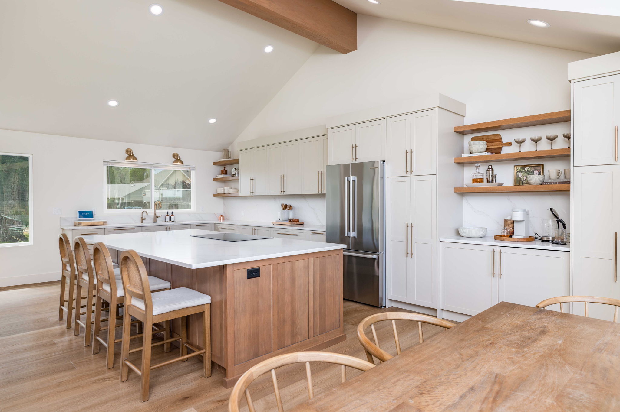 Kitchen featuring an expansive island with a white countertop, light wood-finish cabinetry, integrated stainless-steel appliances, open shelving, and recessed lighting