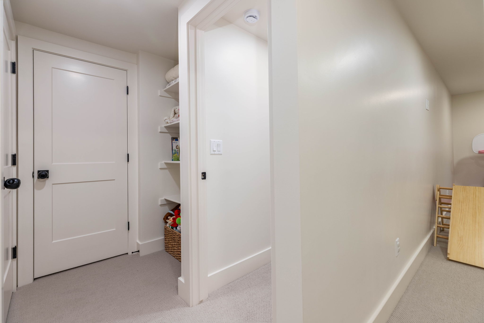 White interior doors with black hardware, recessed shelving, neutral wall paint, white baseboards, and carpeted flooring