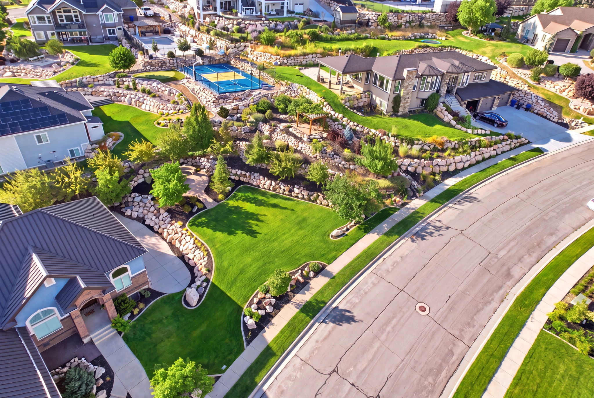 Extensive terraced landscaping featuring rock retaining walls, mature trees, and shrubs
