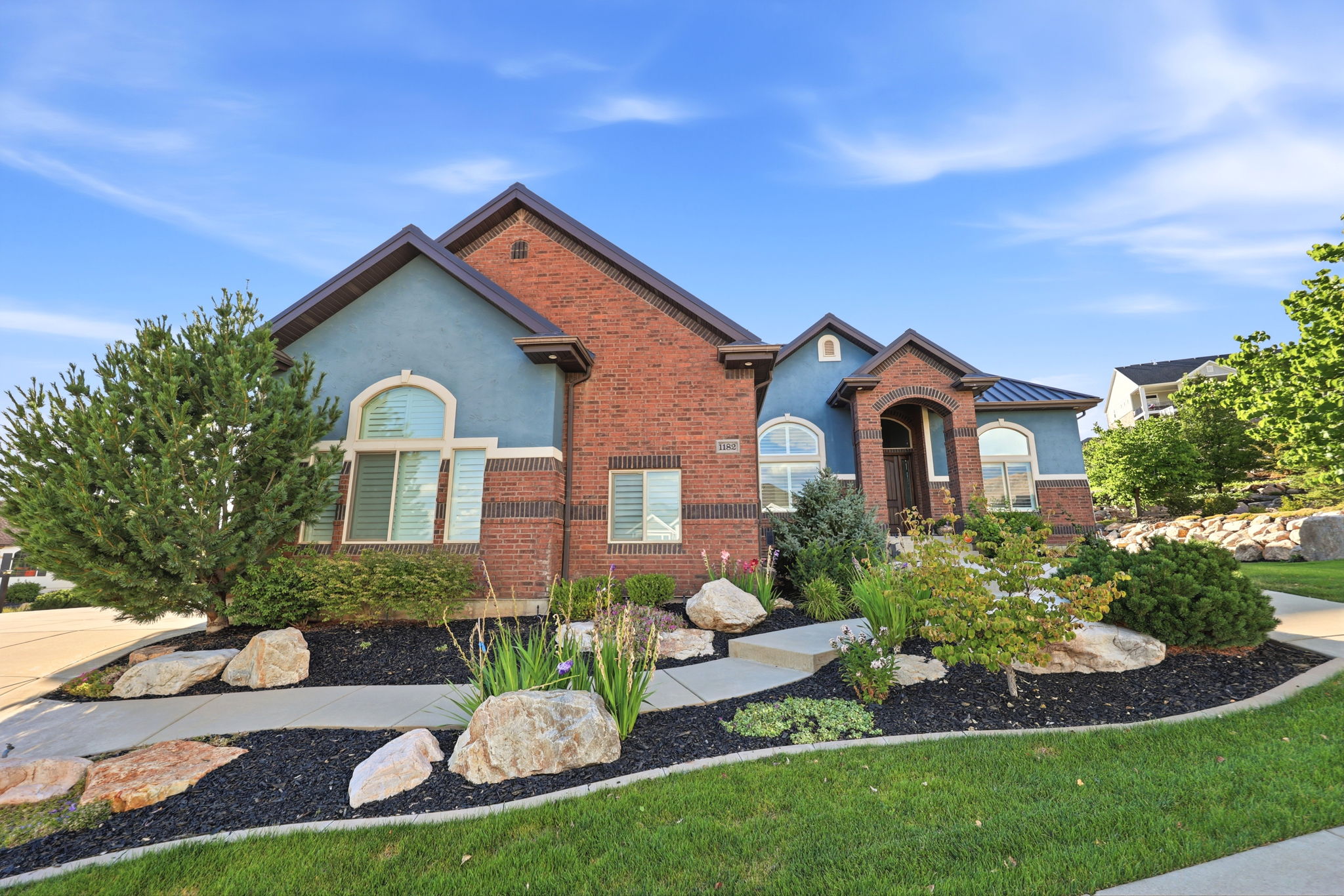 Brick and stucco exterior featuring a covered entry and arched windows