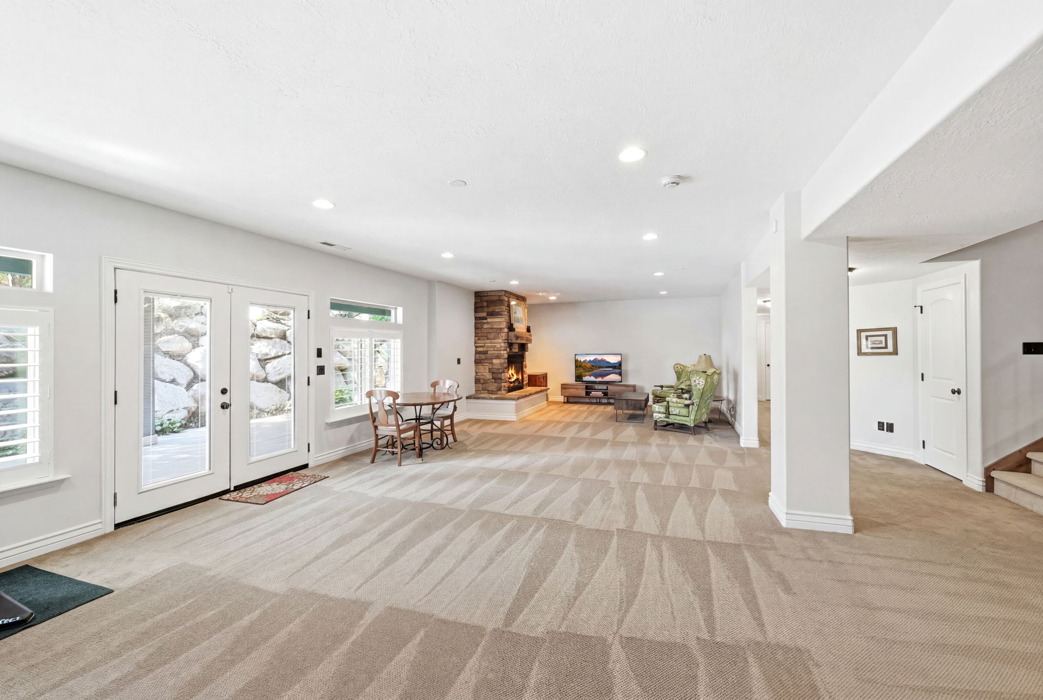 Spacious room featuring broadloom carpeting, a stone-clad fireplace, and recessed lighting