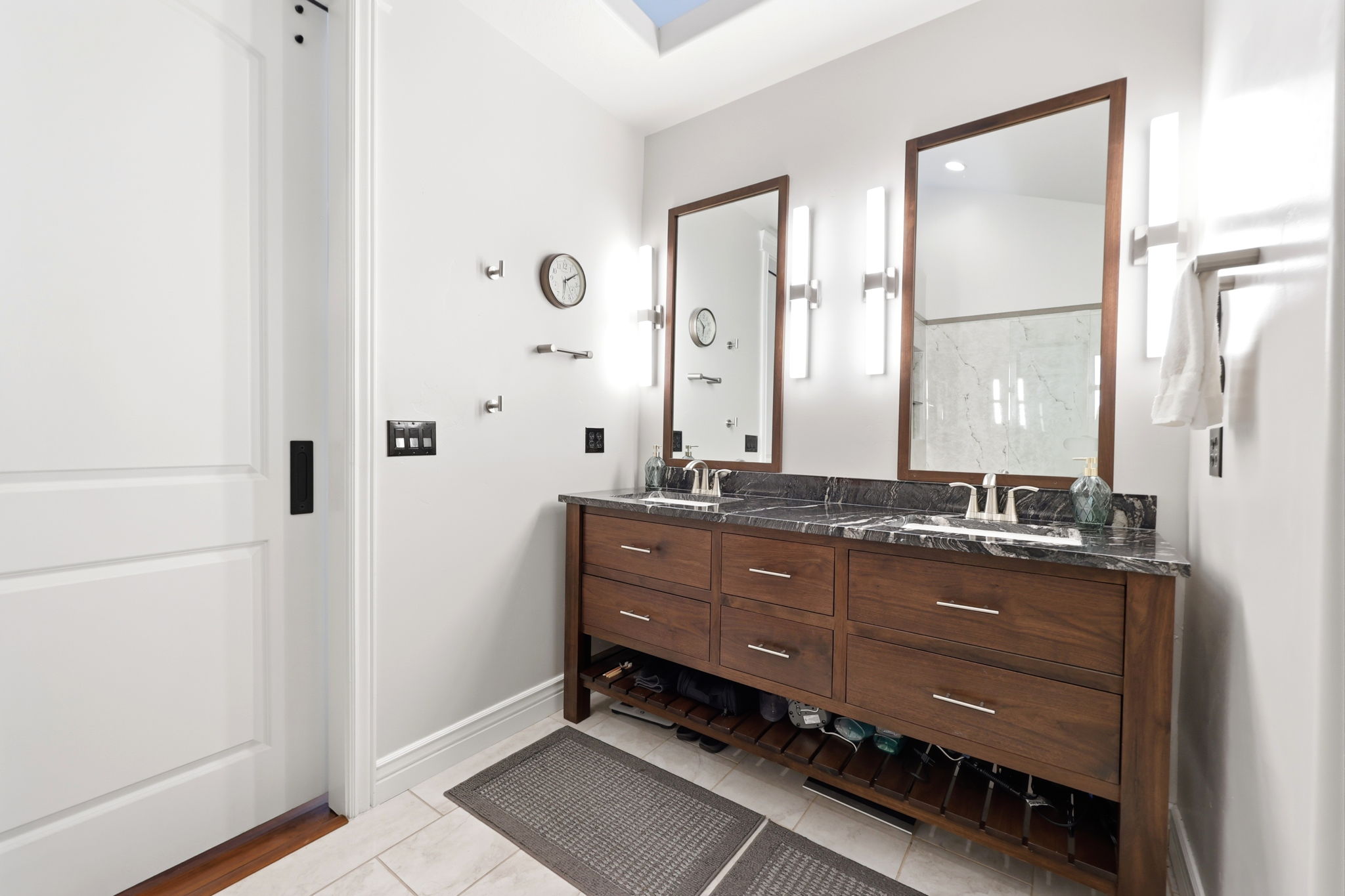 Double vanity featuring wood cabinetry, a dark stone countertop, undermount sinks, and individual framed mirrors