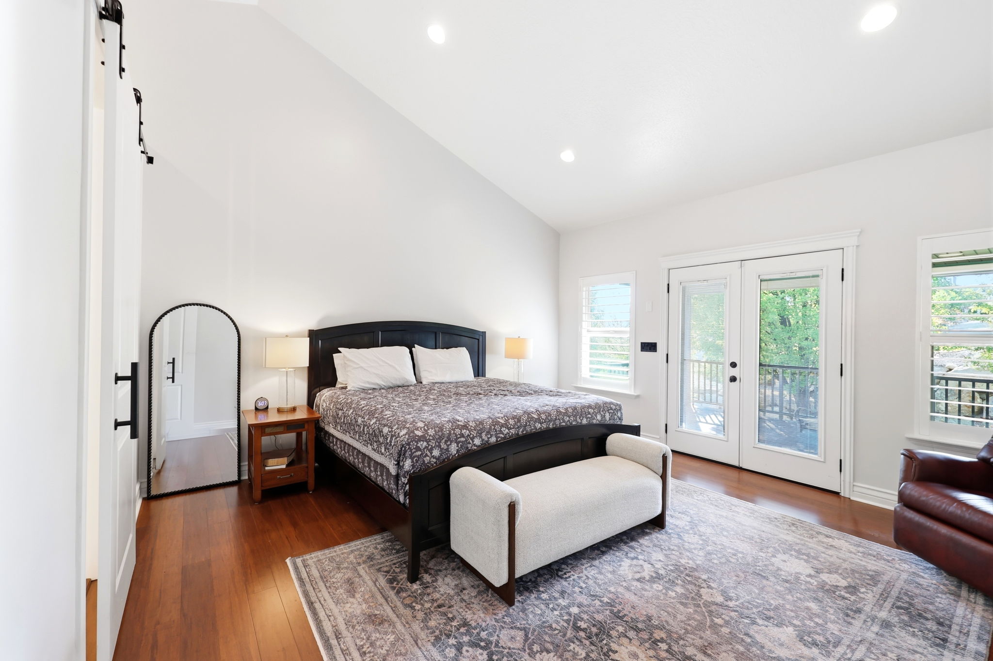 Vaulted ceiling room featuring wood-finish flooring, recessed lighting, and a barn door entry