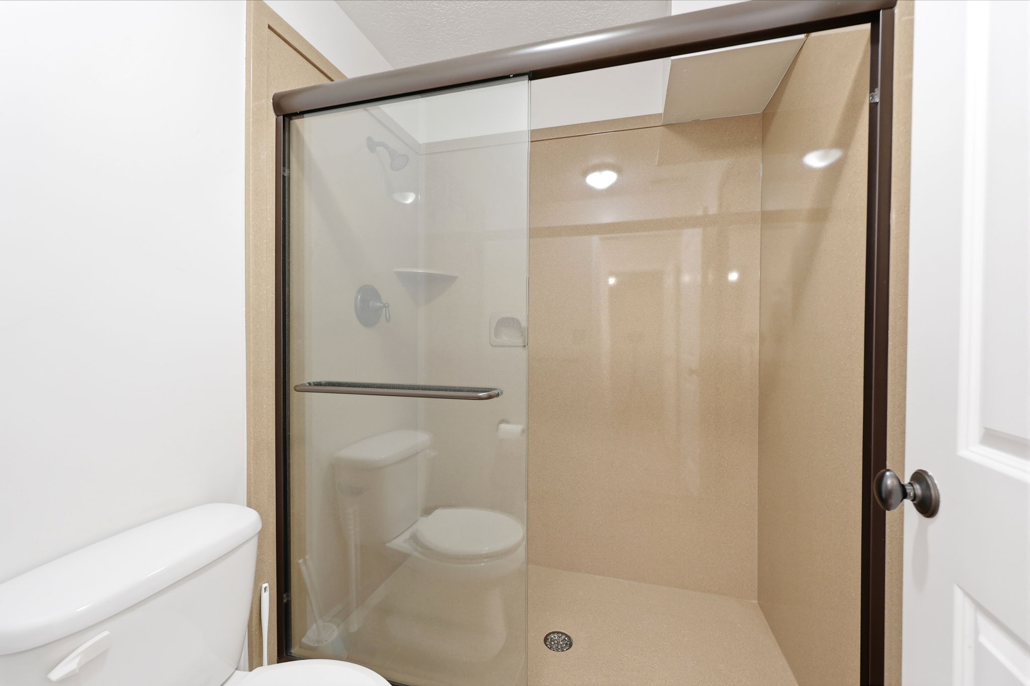 Walk-in shower with clear glass enclosure and dark bronze framing