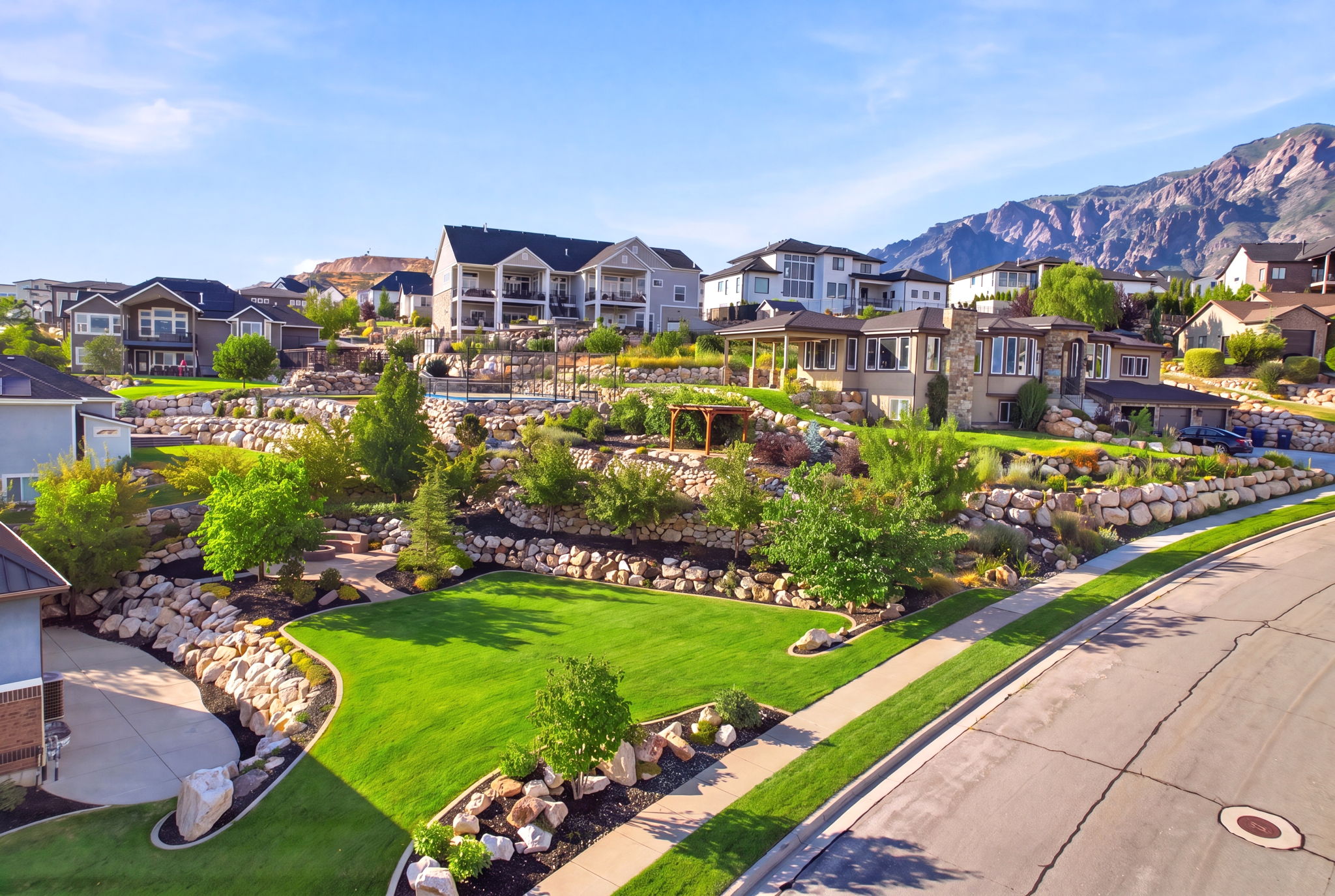 Expansive terraced landscaping featuring rock retaining walls, mature trees, and manicured lawns