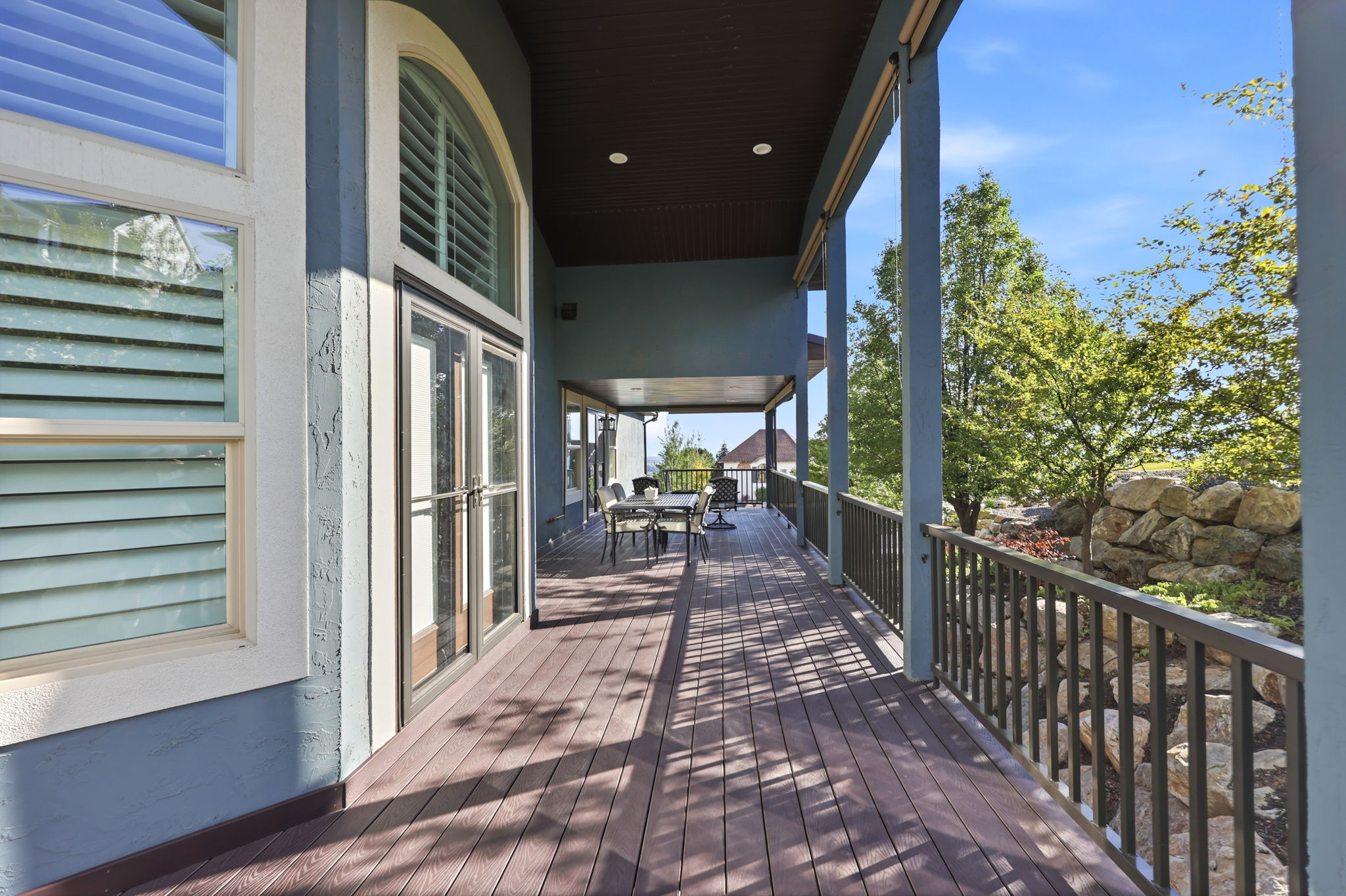 Expansive exterior deck featuring wood-finish flooring, a metal railing system, and a stucco exterior