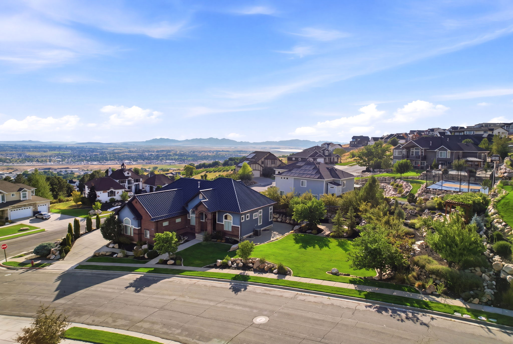 Expansive property featuring a multi-story residence with a dark metal roof, brick and siding exterior, and a manicured front lawn