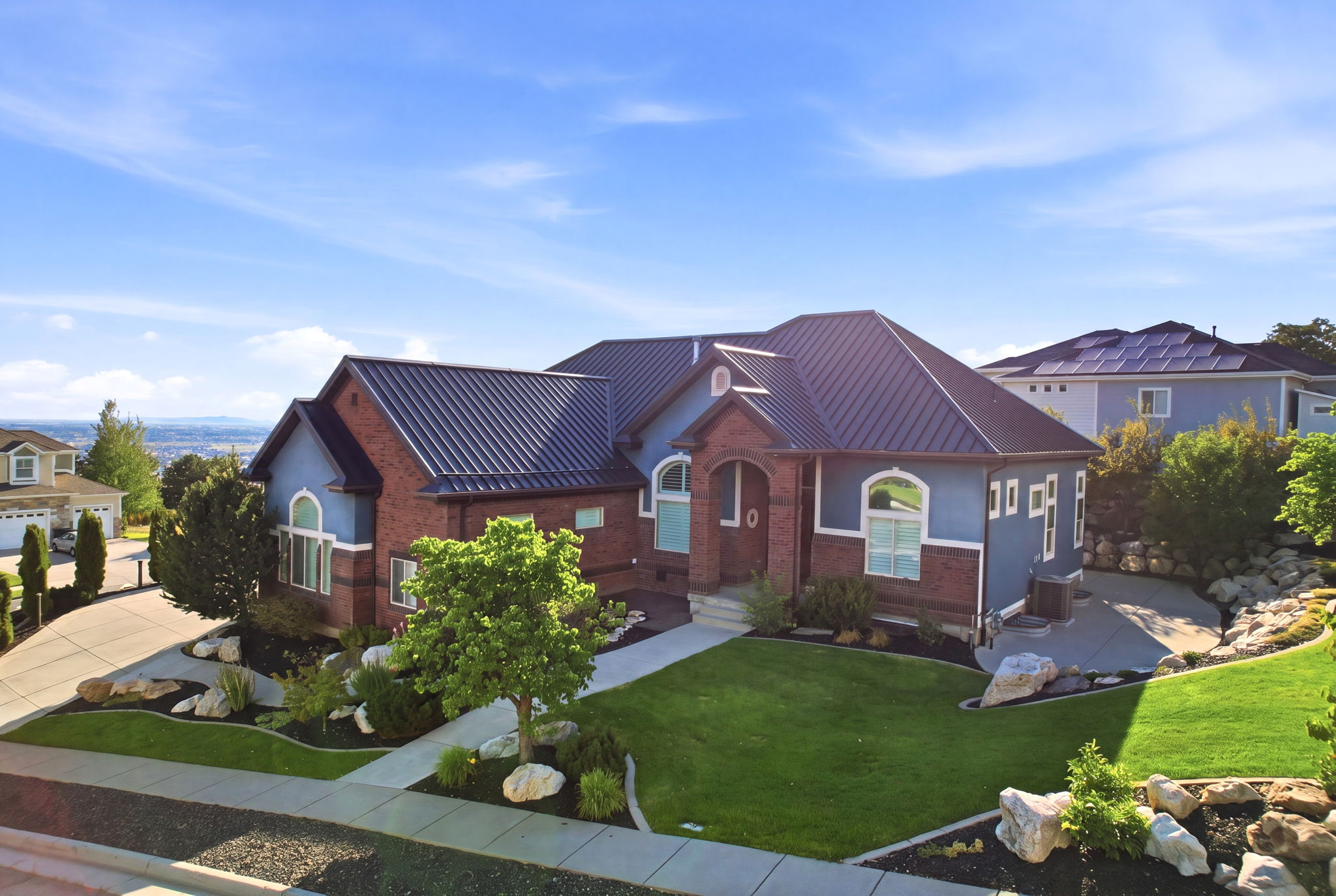 Brick and siding exterior featuring a dark metal roof, arched entryway, and multiple windows