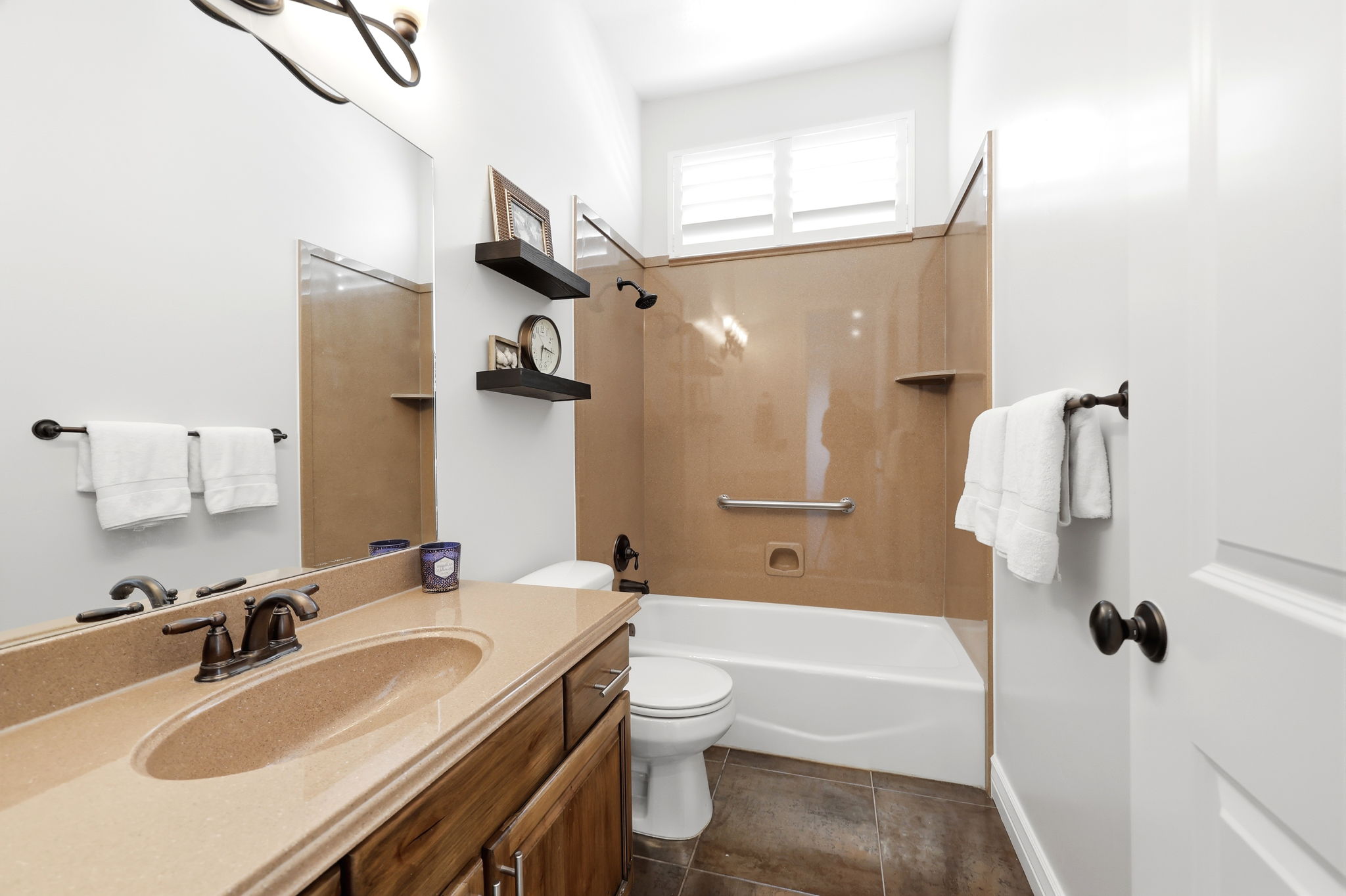Bathroom vanity featuring a single integrated sink with a bronze-finish faucet, wood cabinetry, and a large wall-mounted mirror