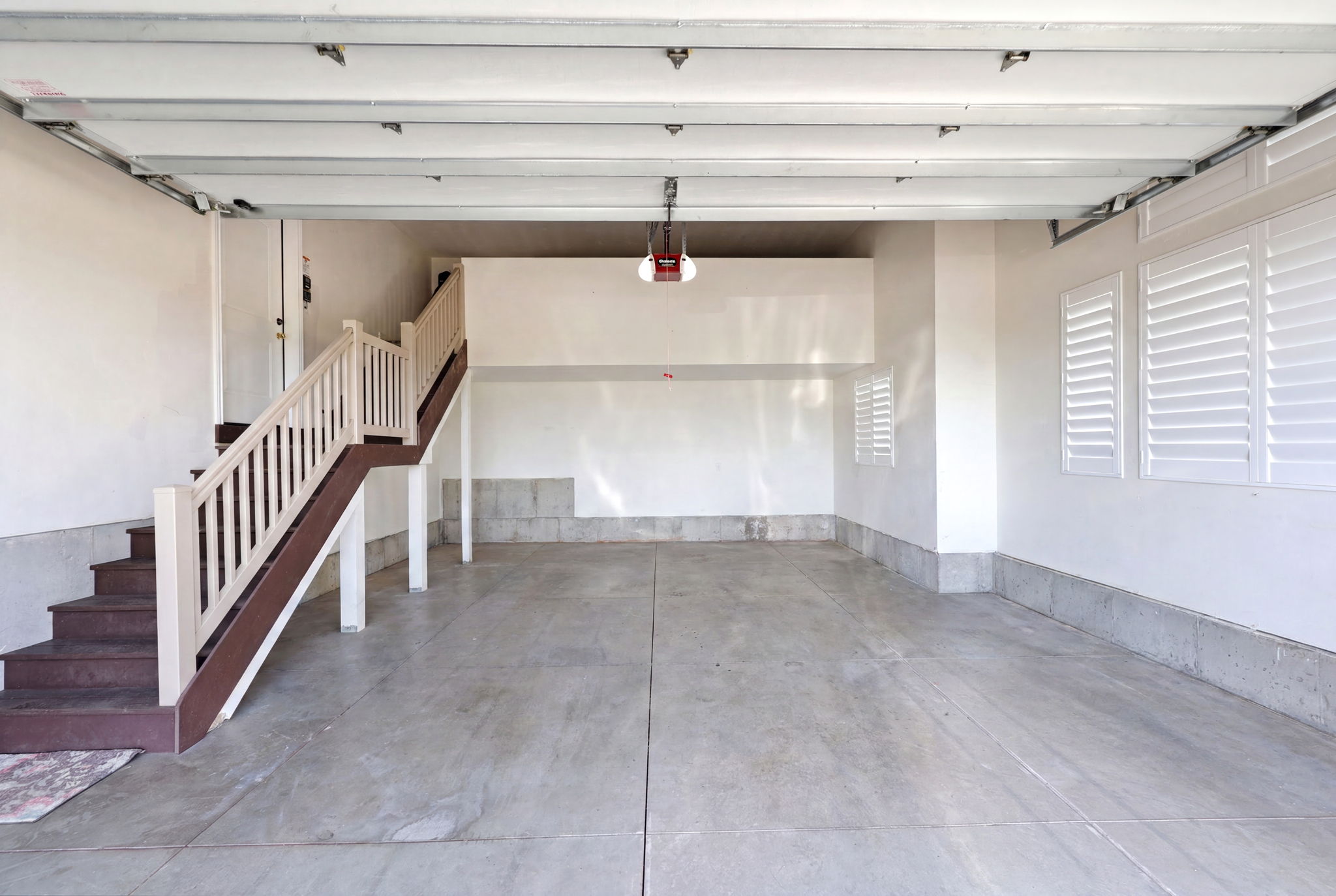 Spacious garage with concrete flooring, white walls, and a visible garage door opener mechanism