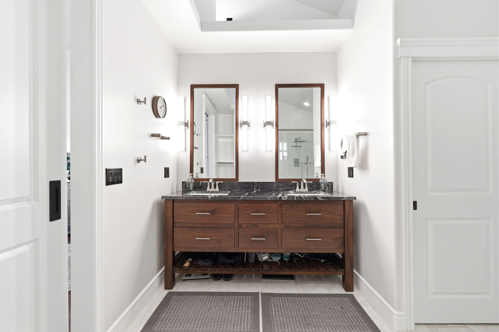 Dual vanity with rich wood-finish cabinetry and a dark stone countertop featuring integrated sinks
