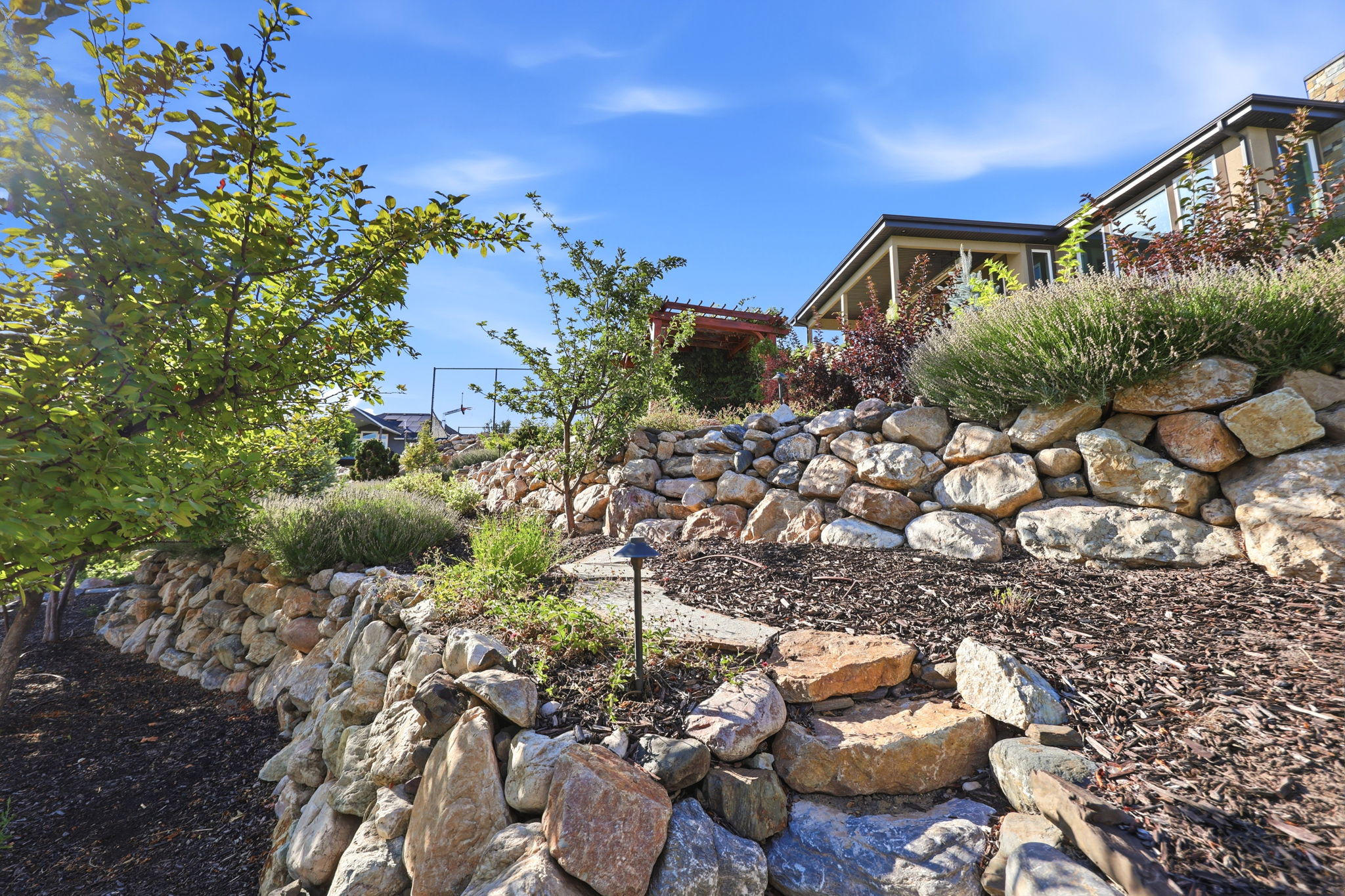 Tiered landscaping featuring natural stone retaining walls and mature plantings