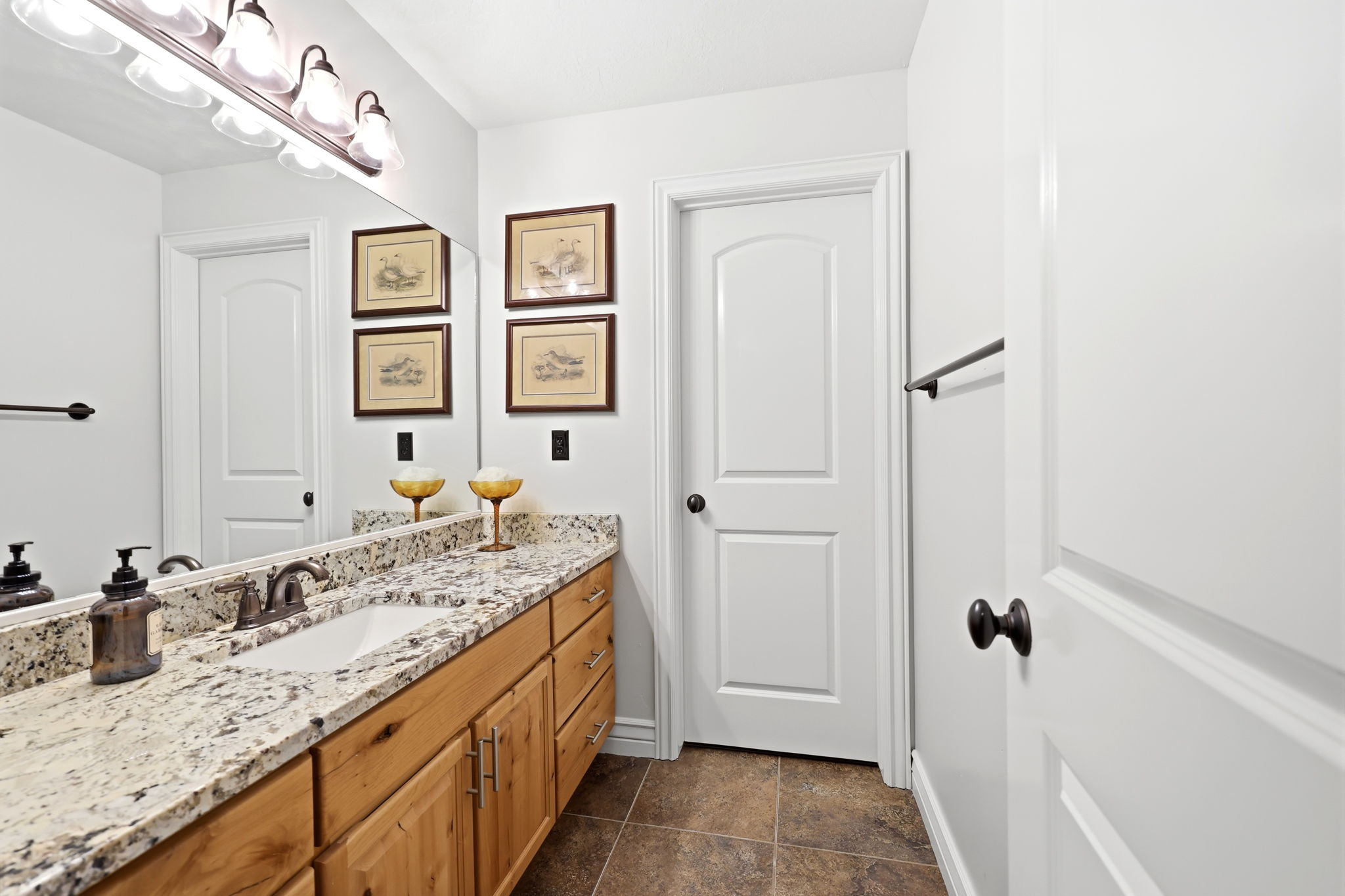 Bathroom vanity featuring a light-toned countertop, undermount sink, and wood-finish cabinetry