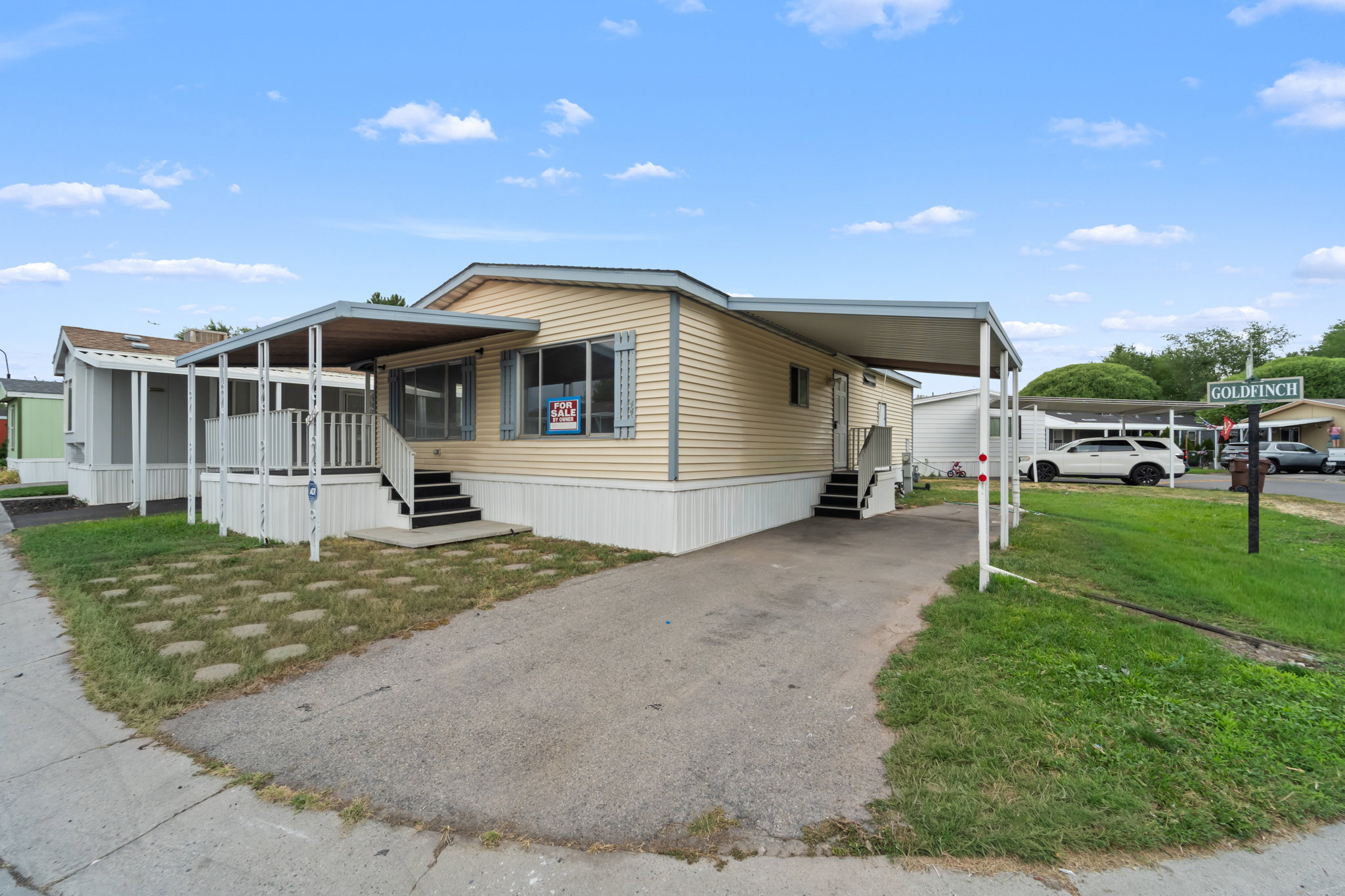 Single-story residence featuring light-colored siding, a covered front porch with railings, and an additional covered carport