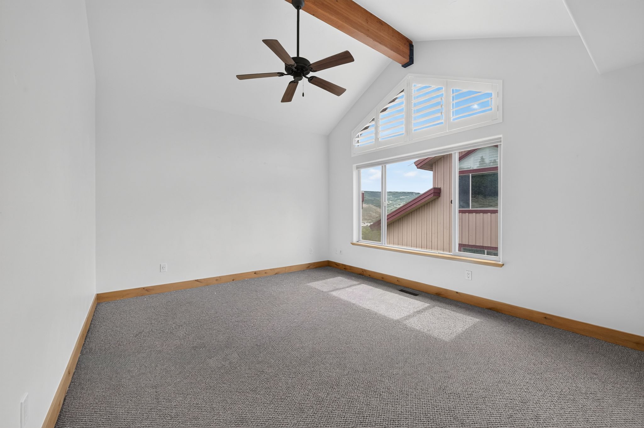 Vaulted ceiling with an exposed wood beam and ceiling fan