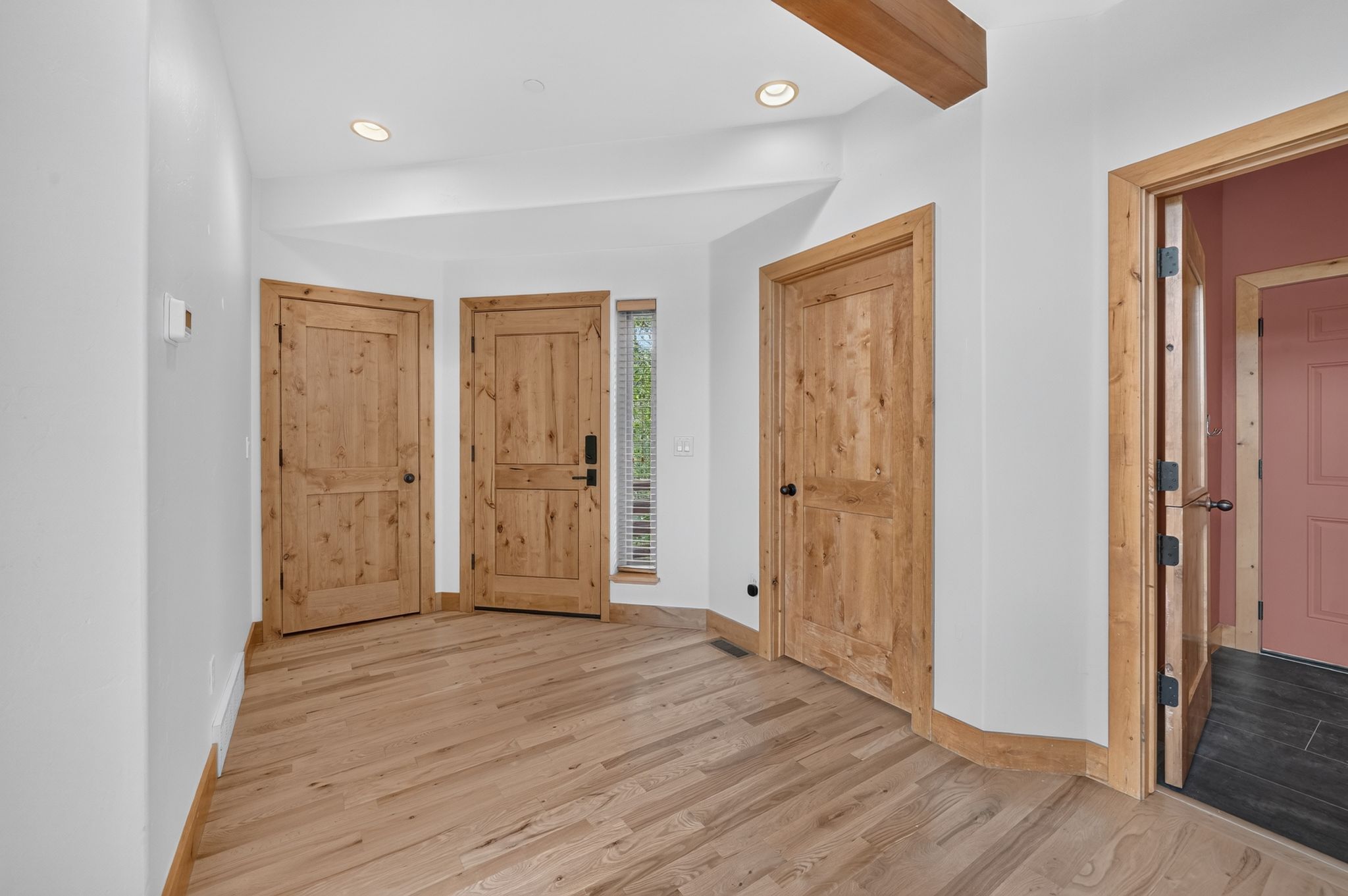 Entryway featuring light wood-finish flooring, recessed lighting, and natural wood doors with black hardware