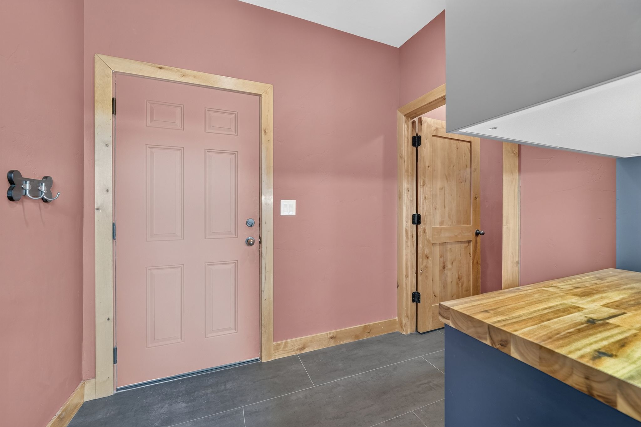 Entryway featuring a panel door with wood trim, grey tile flooring, and a built-in butcher block countertop