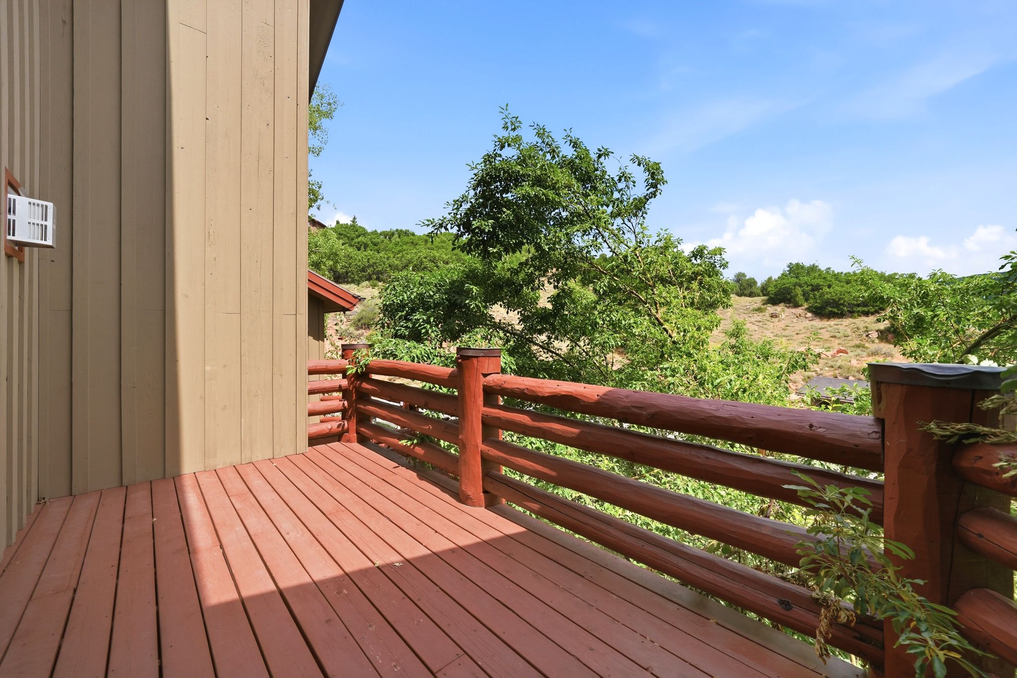 Outdoor deck with rich wood-finish flooring and a log-style railing