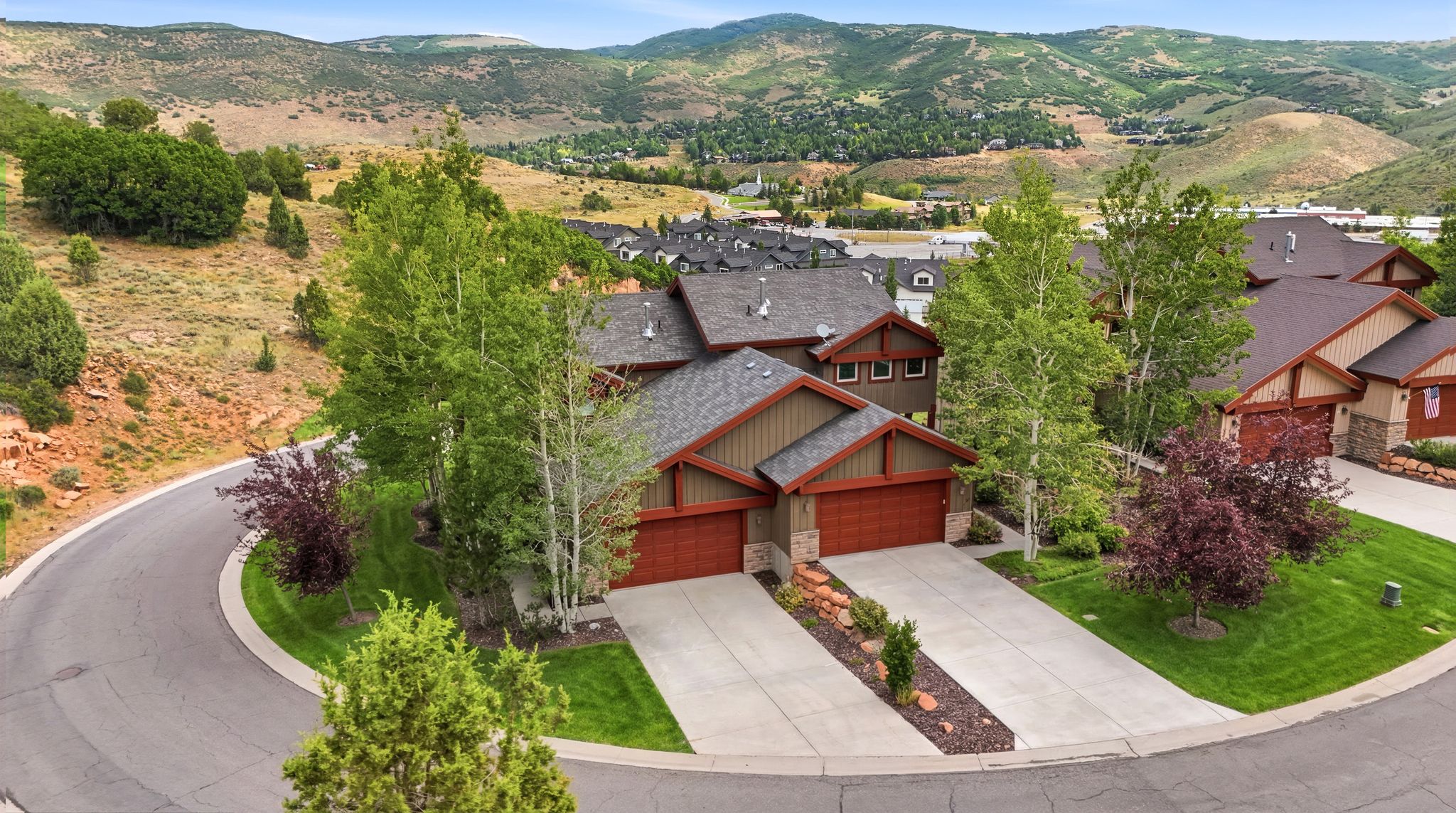 Mountain-style residence featuring a two-car garage, stone and siding exterior, and a paved driveway
