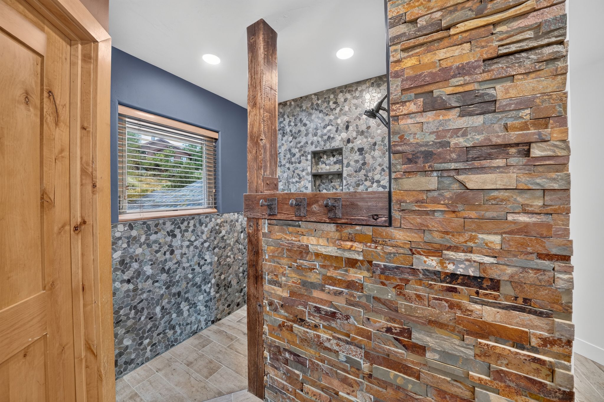 Shower featuring a river rock tile surround and a built-in niche