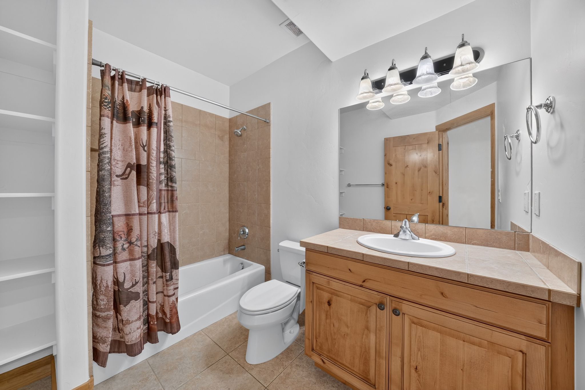 Bathroom featuring a full vanity with wood cabinetry, a tiled countertop, and an integrated sink