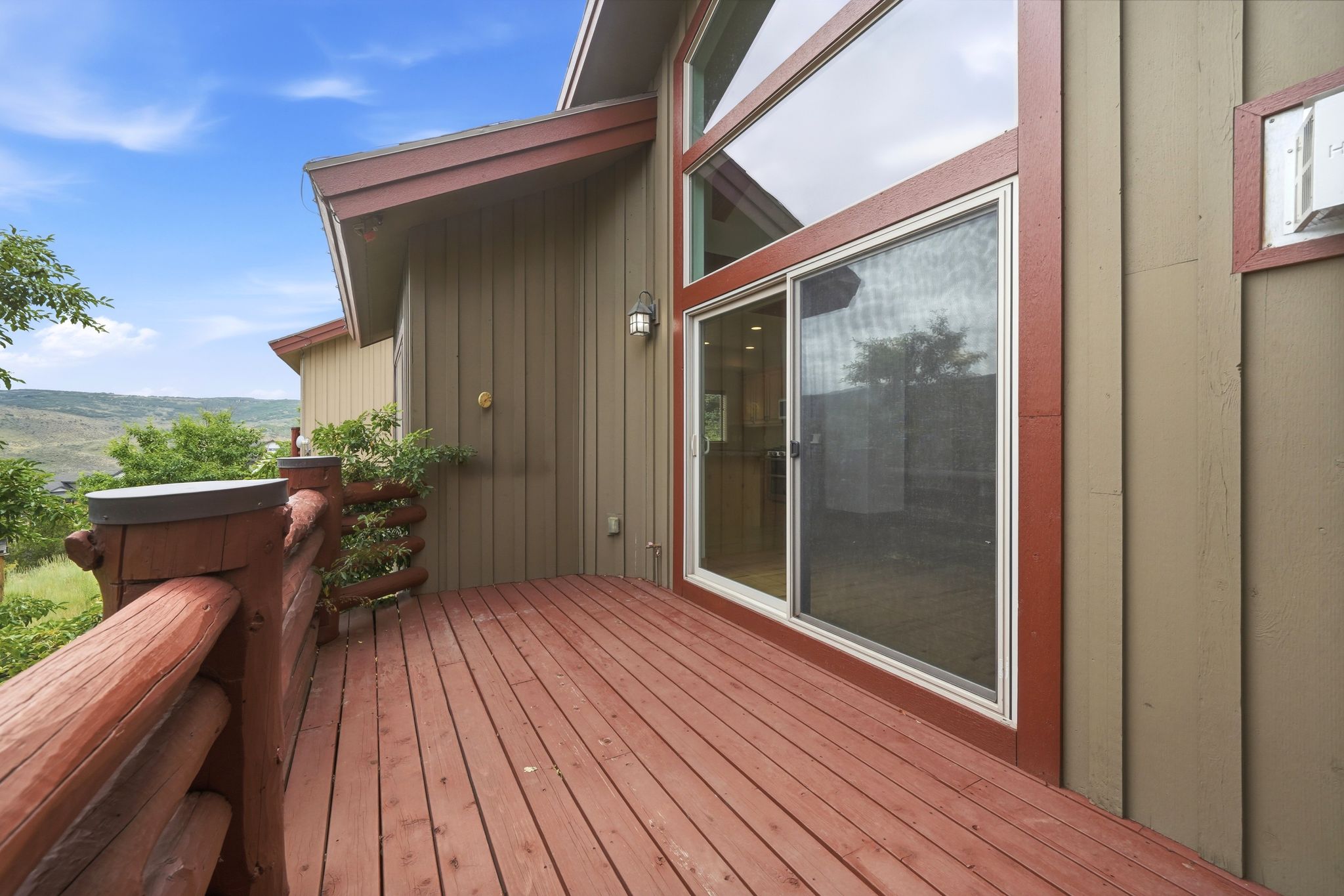 Expansive wooden deck featuring rustic log railings and a sliding glass door