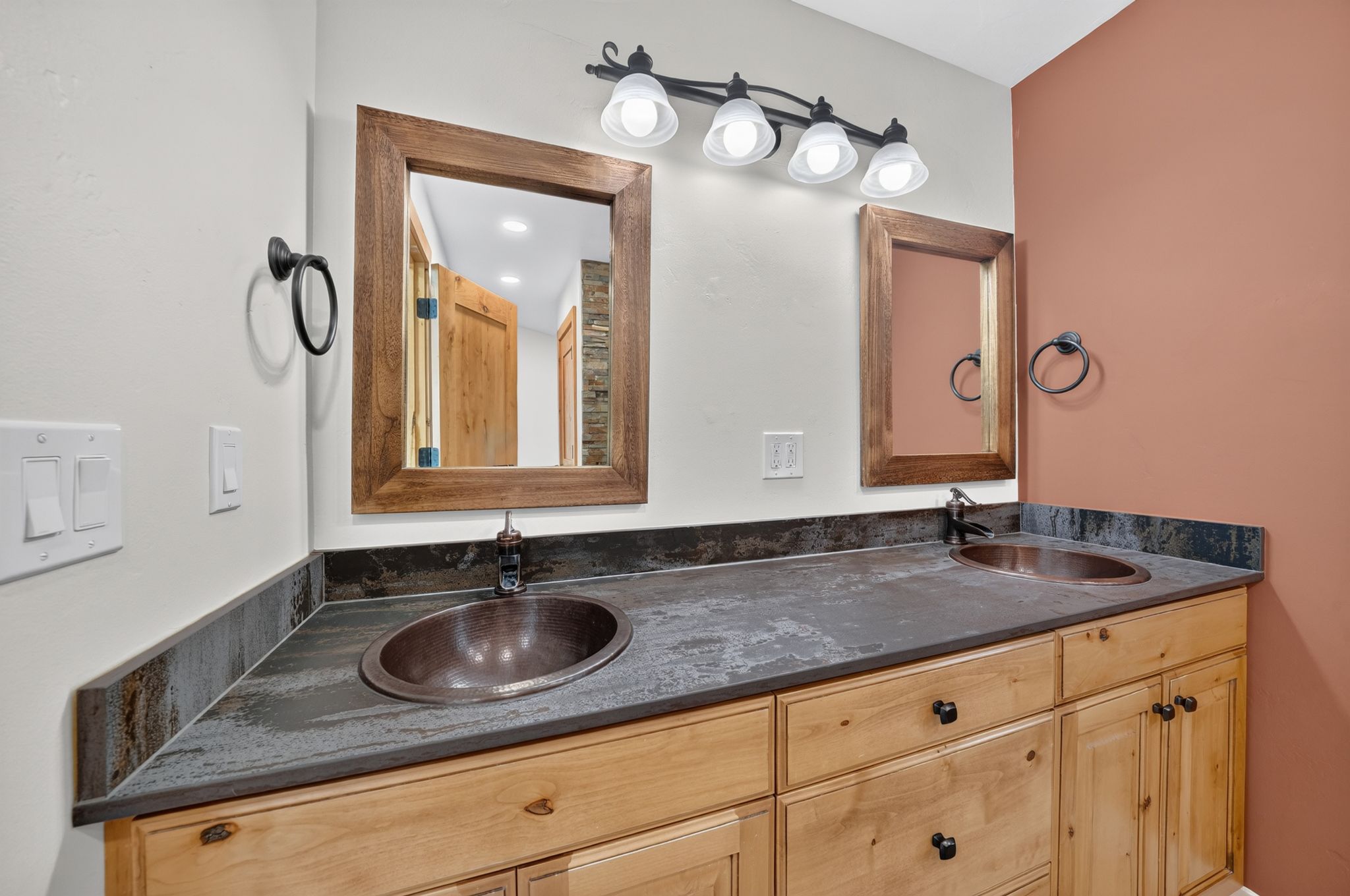 Dual copper vessel sinks with bronze-finish faucets set into a dark countertop with matching backsplash