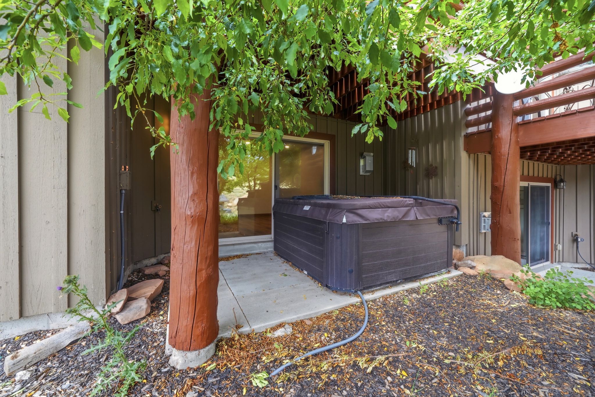 Outdoor hot tub on a concrete patio with surrounding natural landscaping