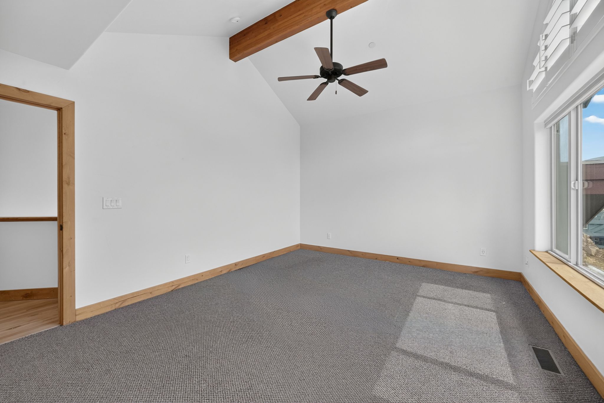 Vaulted ceiling with an exposed wood beam, integrated ceiling fan, and recessed lighting