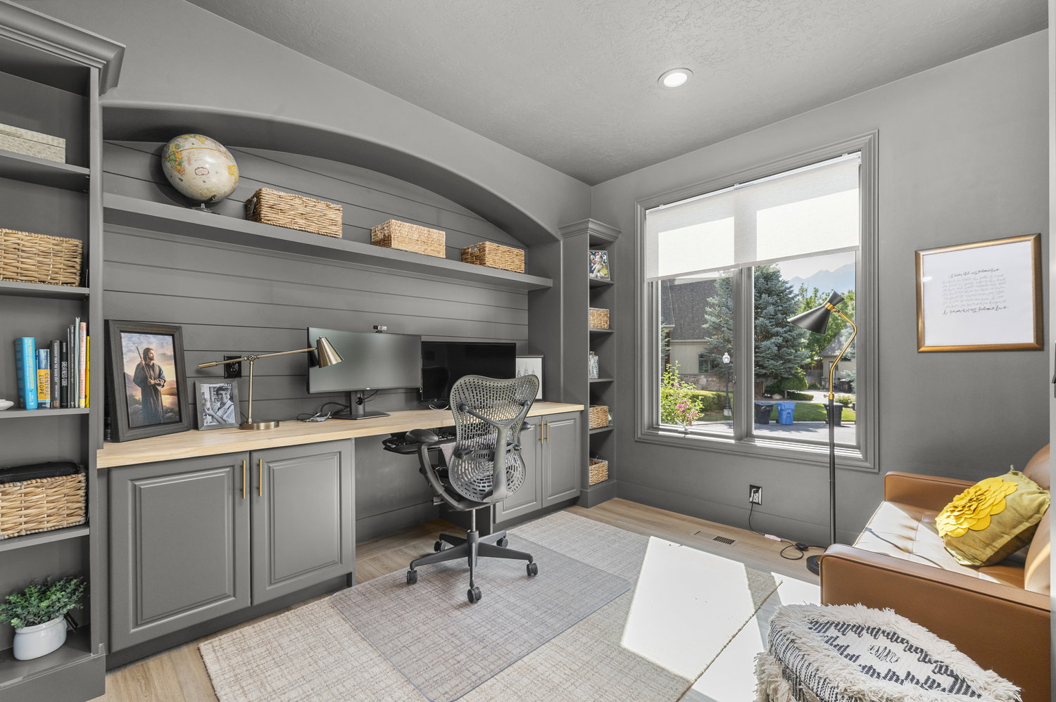 Dedicated workspace featuring custom built-in cabinetry with wood-finish countertops and integrated shelving