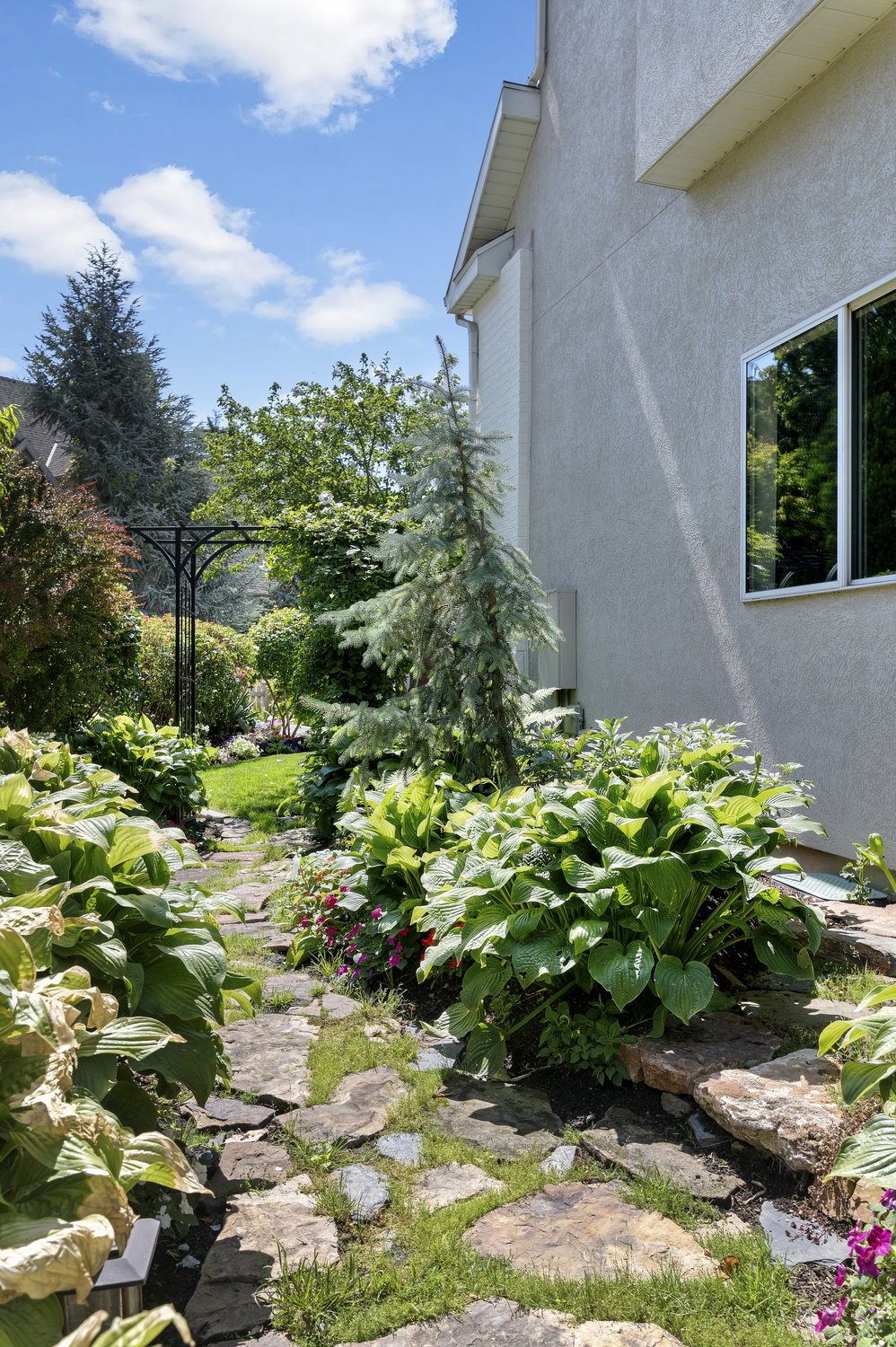 Stone pathway bordered by lush plantings and mature trees