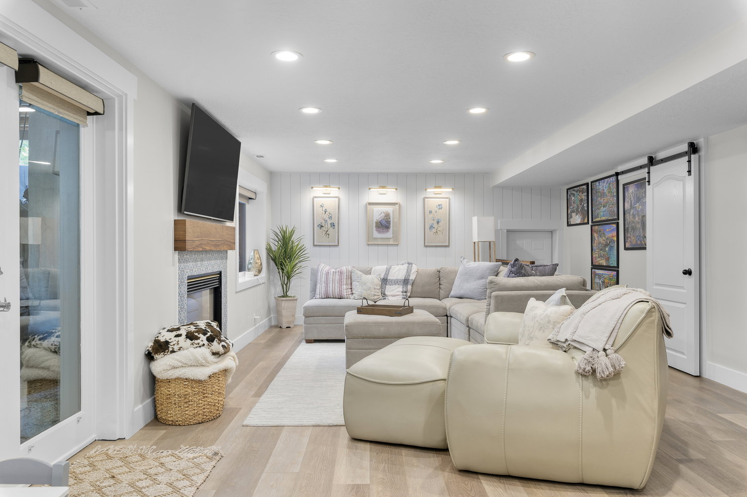 Spacious living area featuring light wood-finish flooring, recessed lighting, and a fireplace with a wood mantle and stone-look surround
