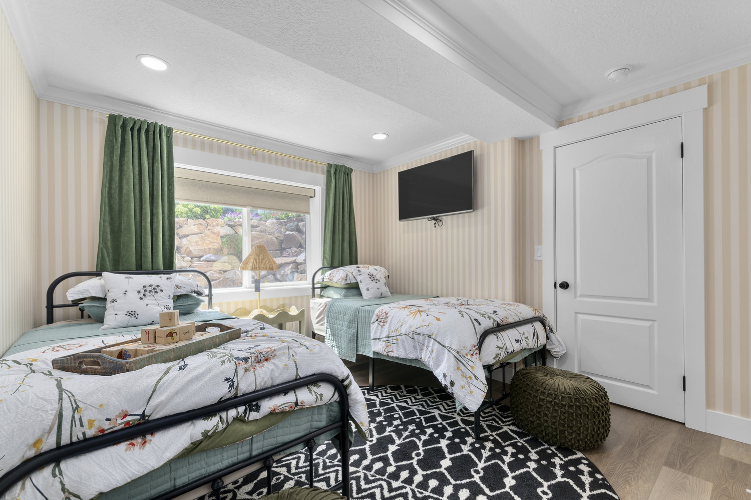 Bedroom featuring wide-striped wallcovering, wood-finish flooring, and a wall-mounted television