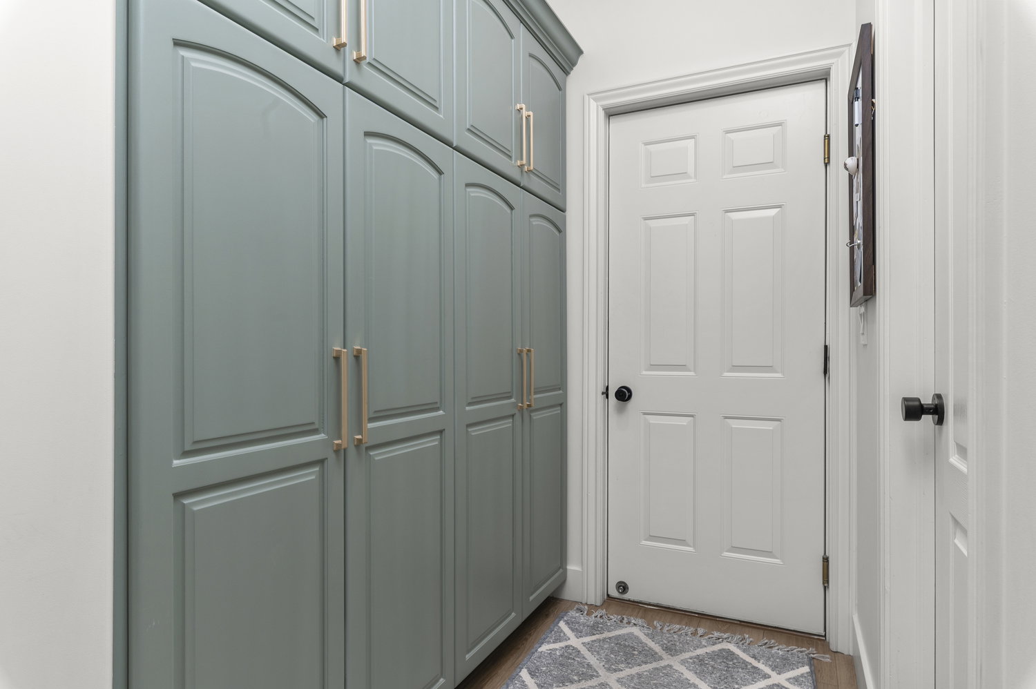 Floor-to-ceiling built-in cabinetry with arched panel doors and gold-tone hardware