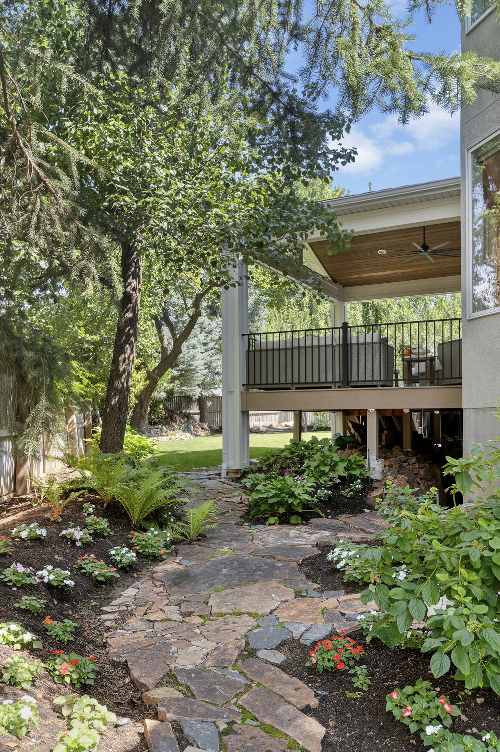 Stone paver pathway bordered by established landscaping, leading to a covered outdoor patio