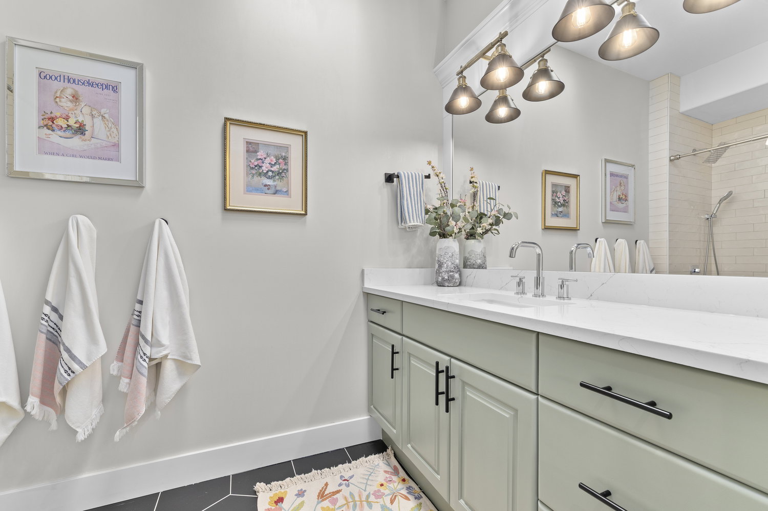 Bathroom vanity featuring light green cabinetry, black hardware, a white countertop, and dual chrome faucets