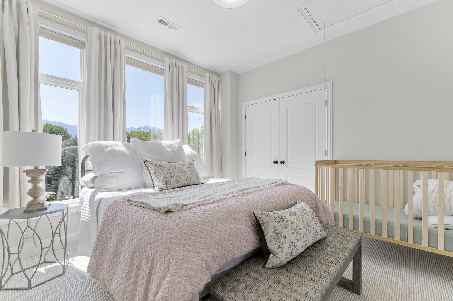 Bedroom featuring a wall of multiple windows overlooking a distant mountain range, light-toned walls, and a ceiling-mounted light fixture