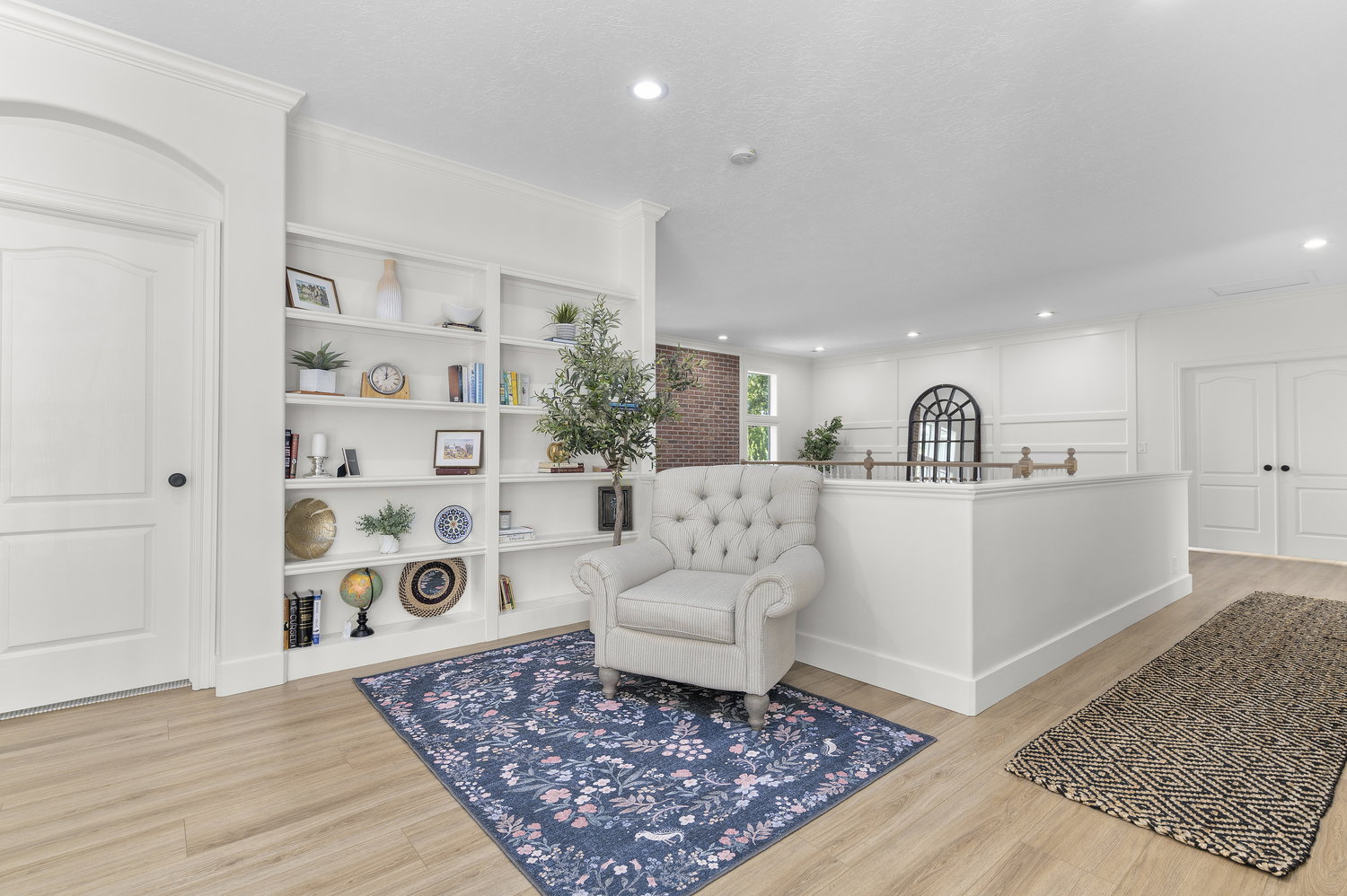 Expansive open concept living area featuring recessed lighting, a built-in shelving unit, wood-finish flooring, and white paneled walls