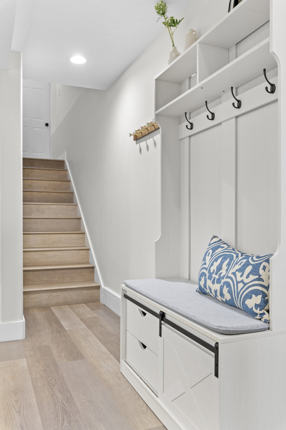 Basement stairs leading to the garage private entrance. Built-in mudroom bench with sliding barn door style storage and open shelving.