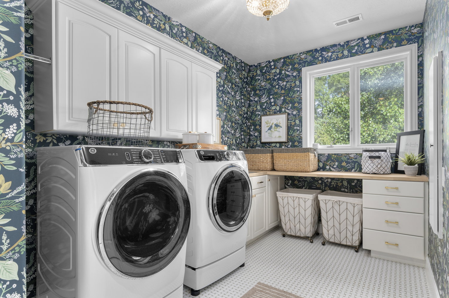 Laundry area featuring patterned wallpaper, white cabinetry, a wood-finish countertop, a double window, and white hexagonal tile flooring