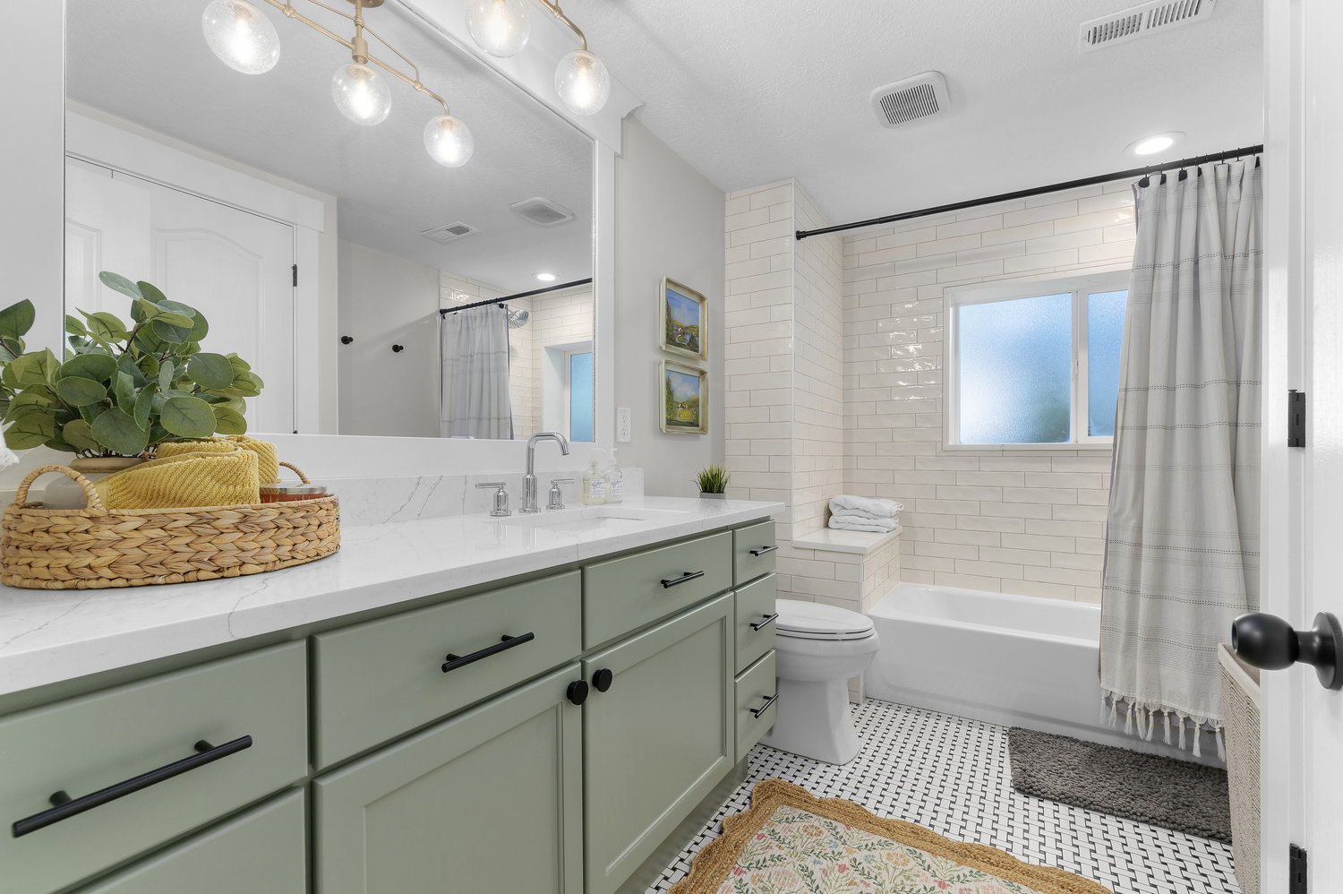 Bathroom featuring a single vanity with light green cabinetry, white countertop, and a large mirror