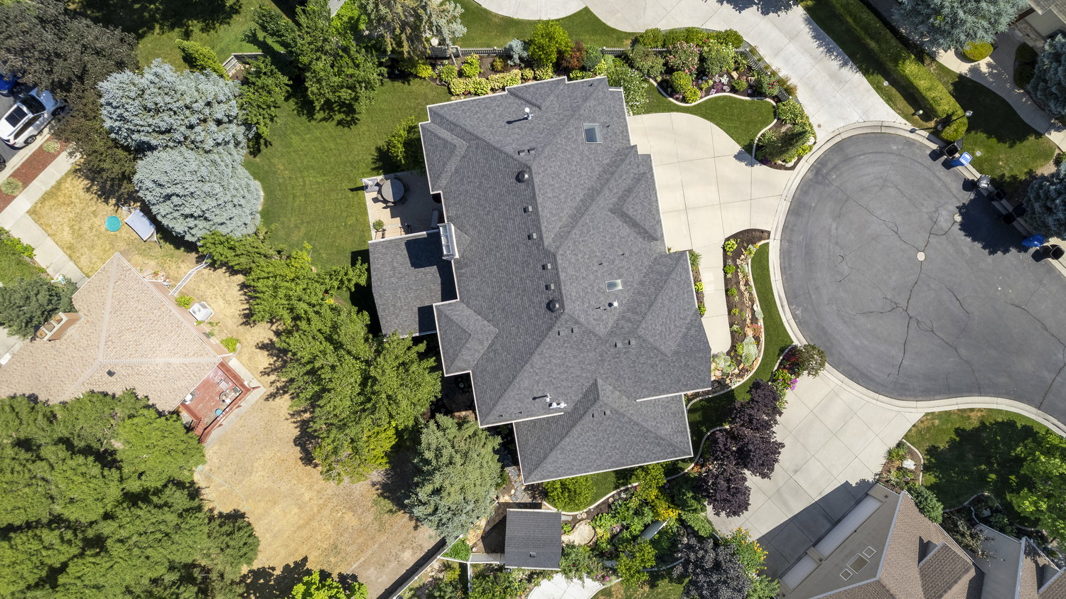 Expansive property featuring a multi-gabled roofline, mature landscaping, a curved driveway, and a private rear patio