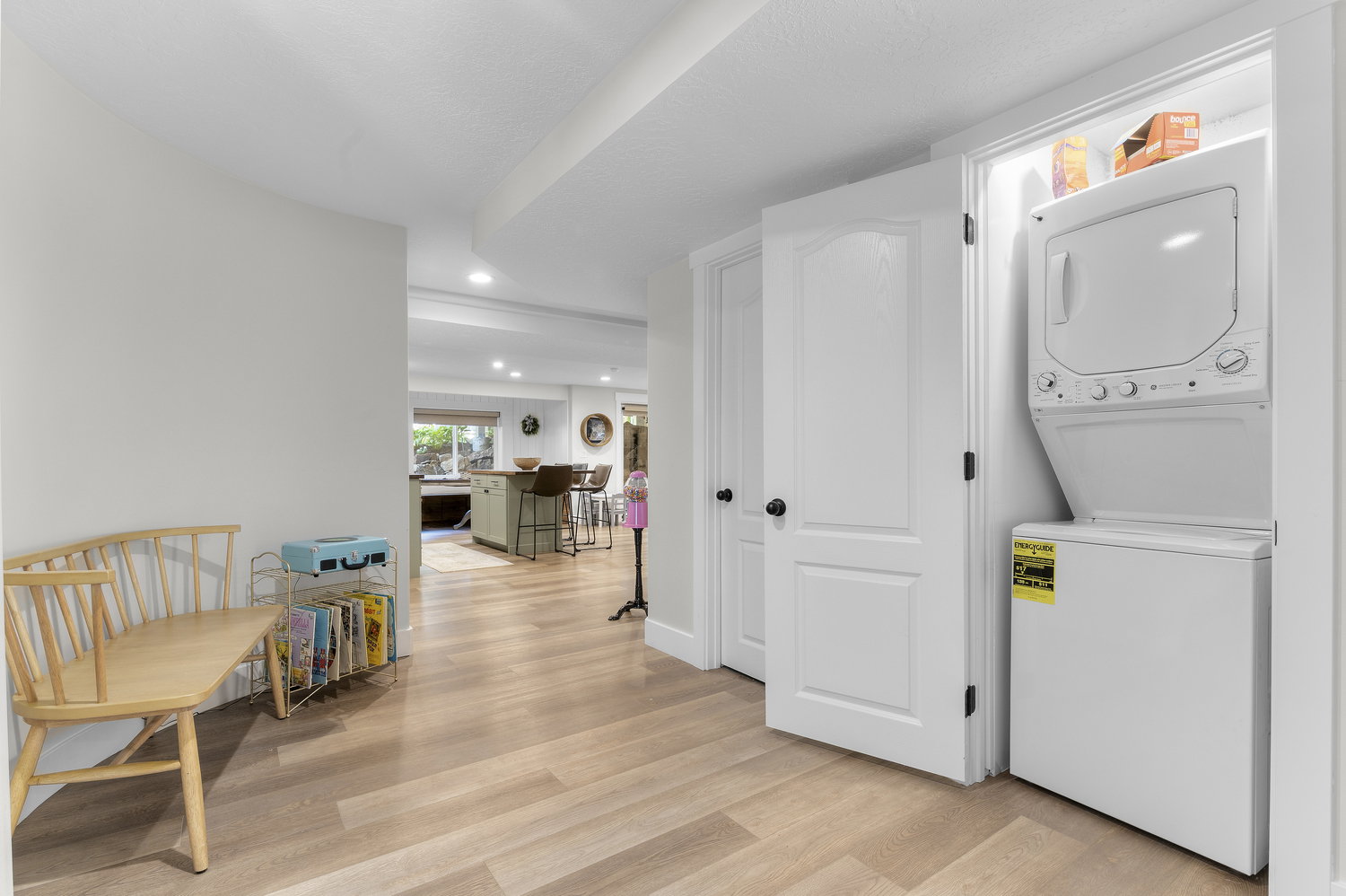 Dedicated laundry closet featuring a stacked white washer and dryer, wood-finish flooring, and white interior doors with black hardware