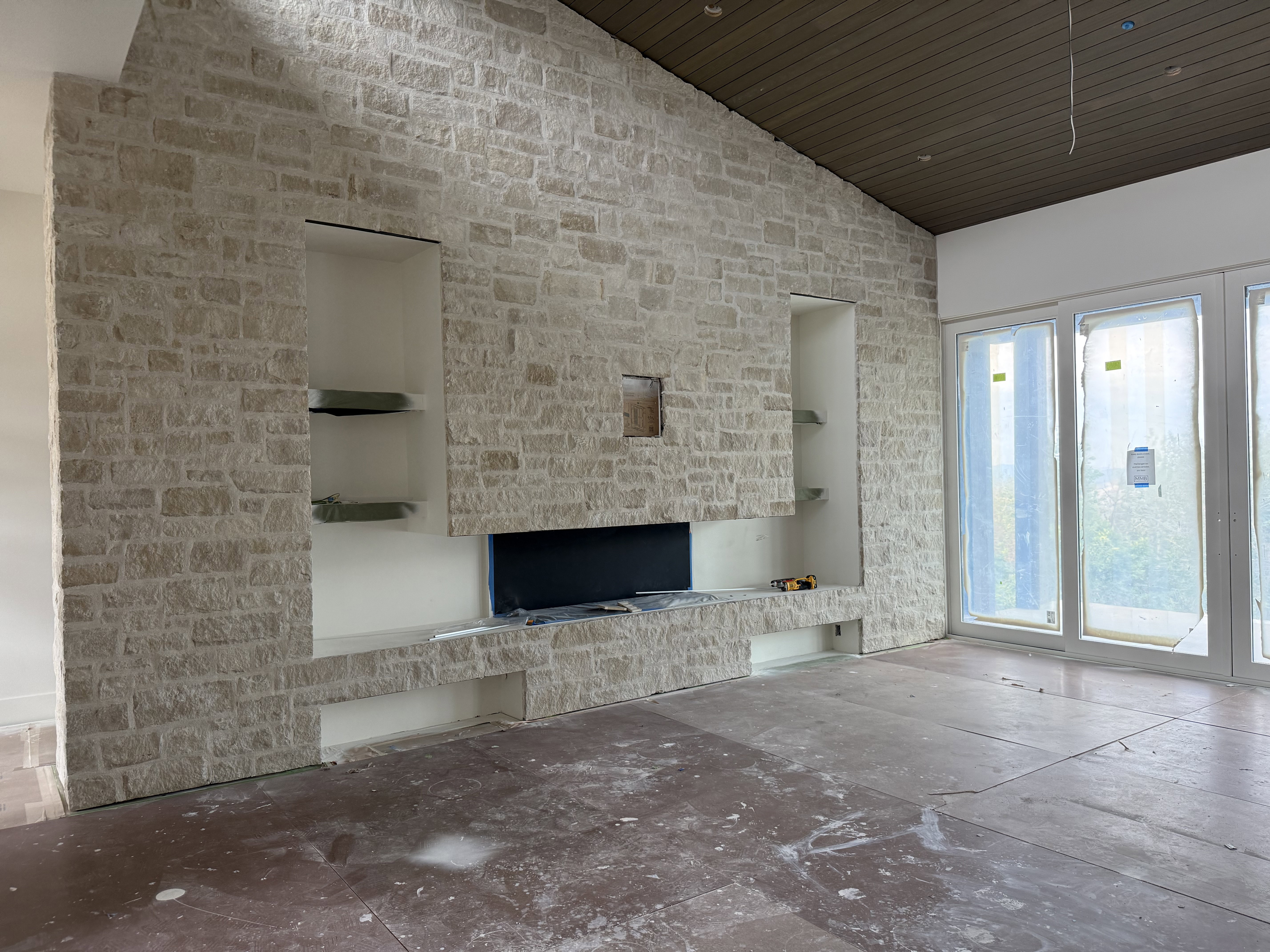Stone accent wall featuring an integrated media console, built-in shelving, and a prominent fireplace opening