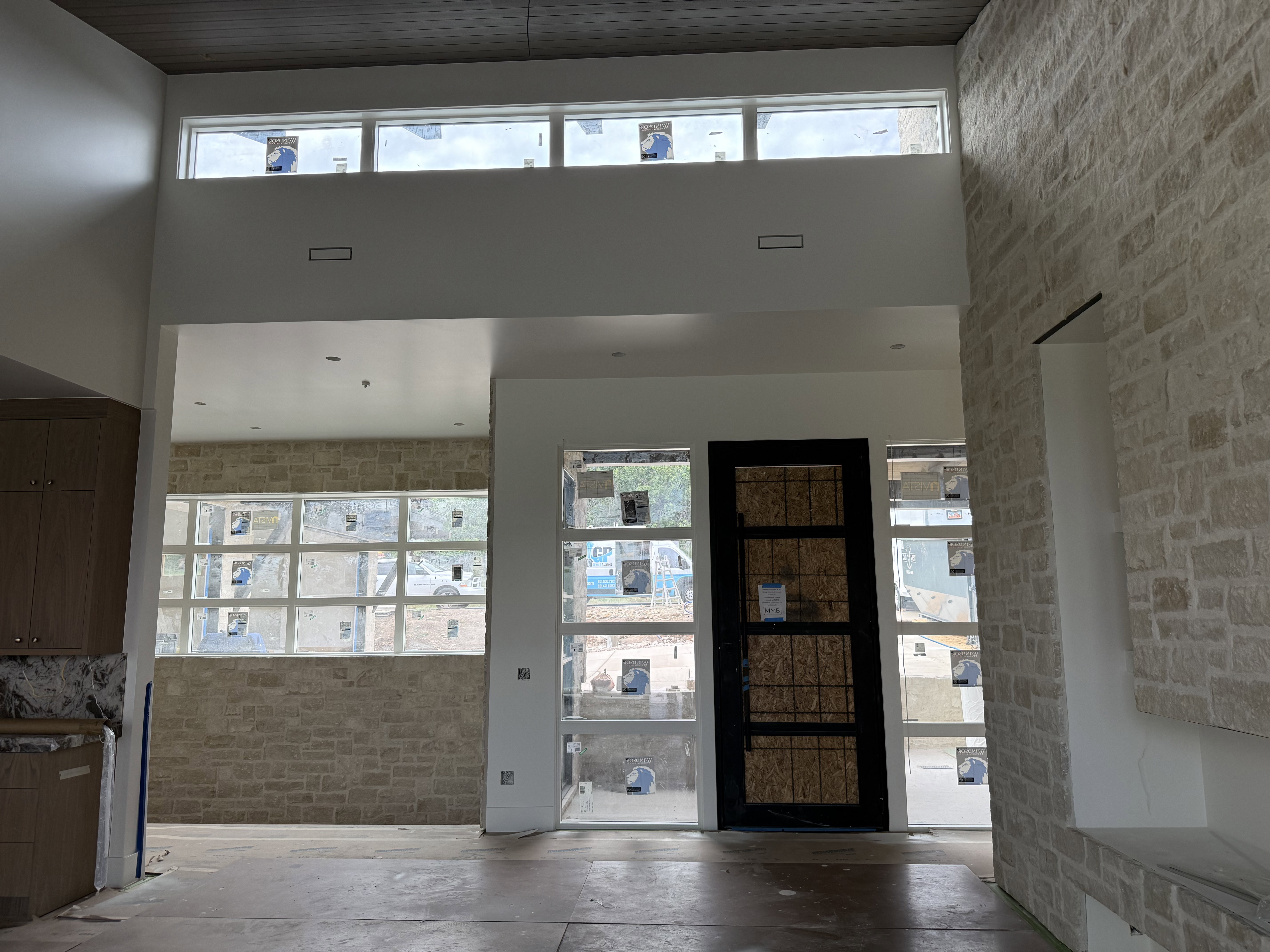 Two-story entry featuring stone accent walls, transom windows, and a multi-paneled dark-framed door