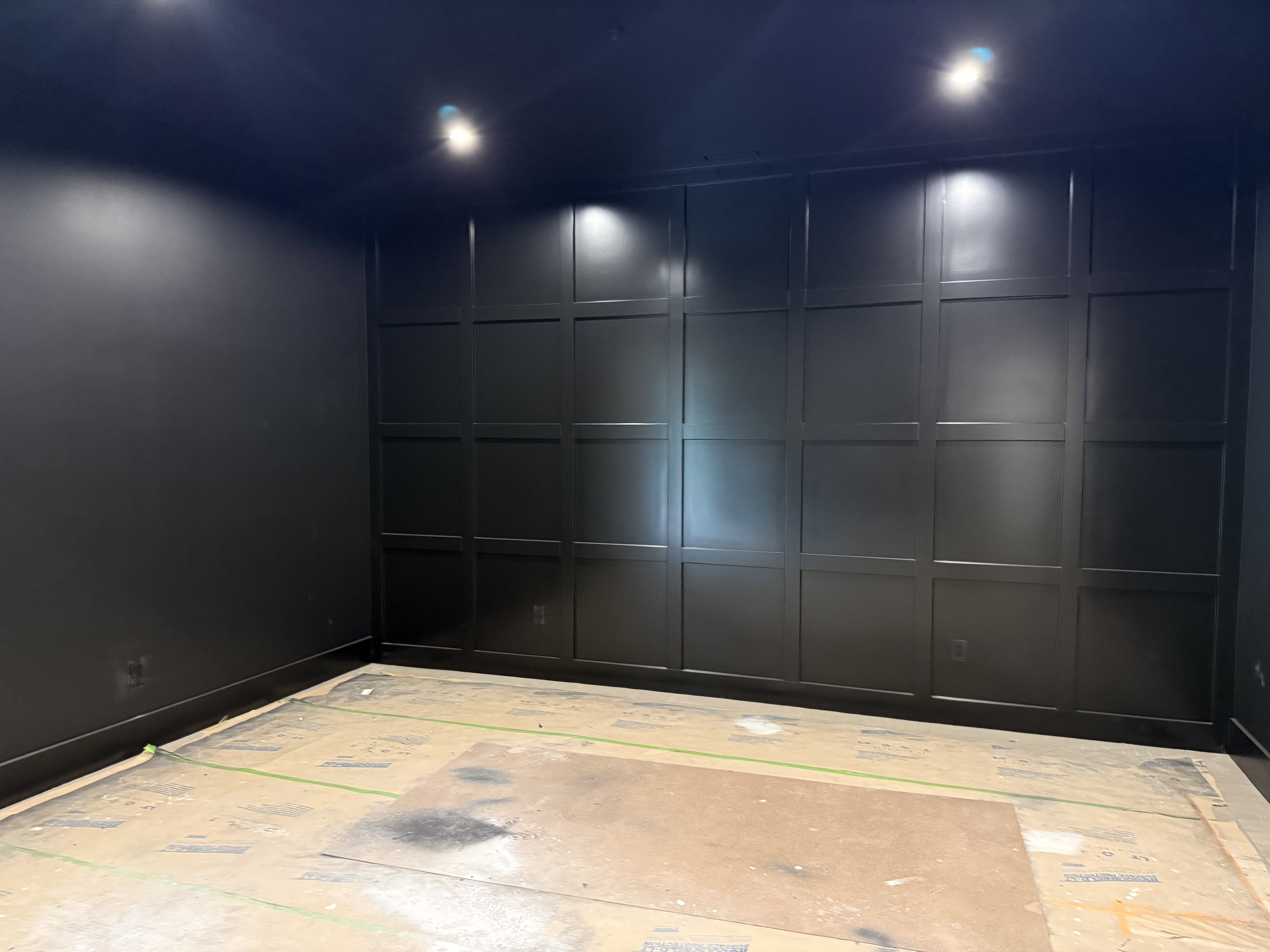Room featuring a full wall of black paneling, black painted walls, and ceiling-mounted recessed lighting