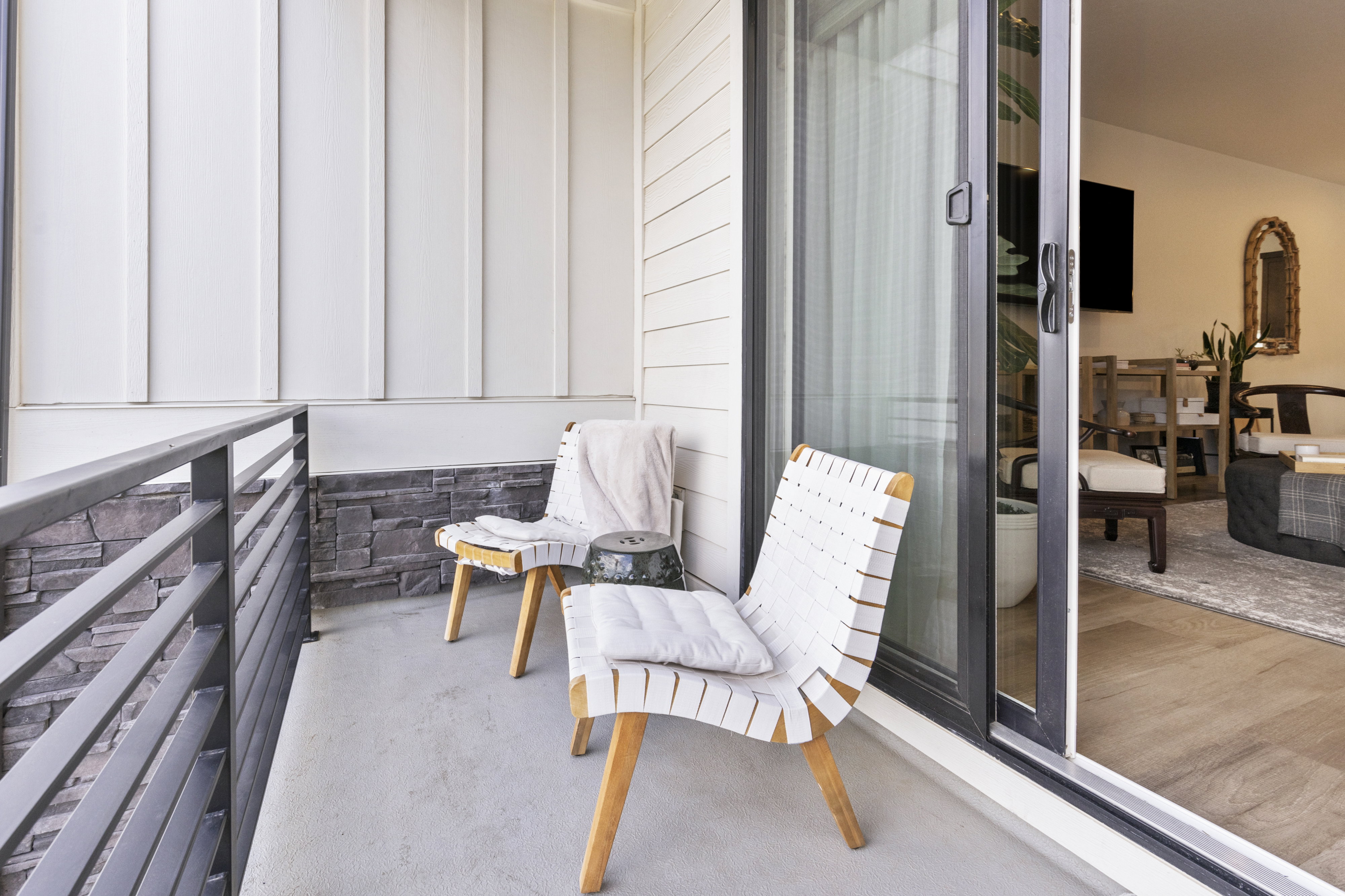 Private balcony featuring horizontal bar railing, stone veneer accents, and board and batten siding