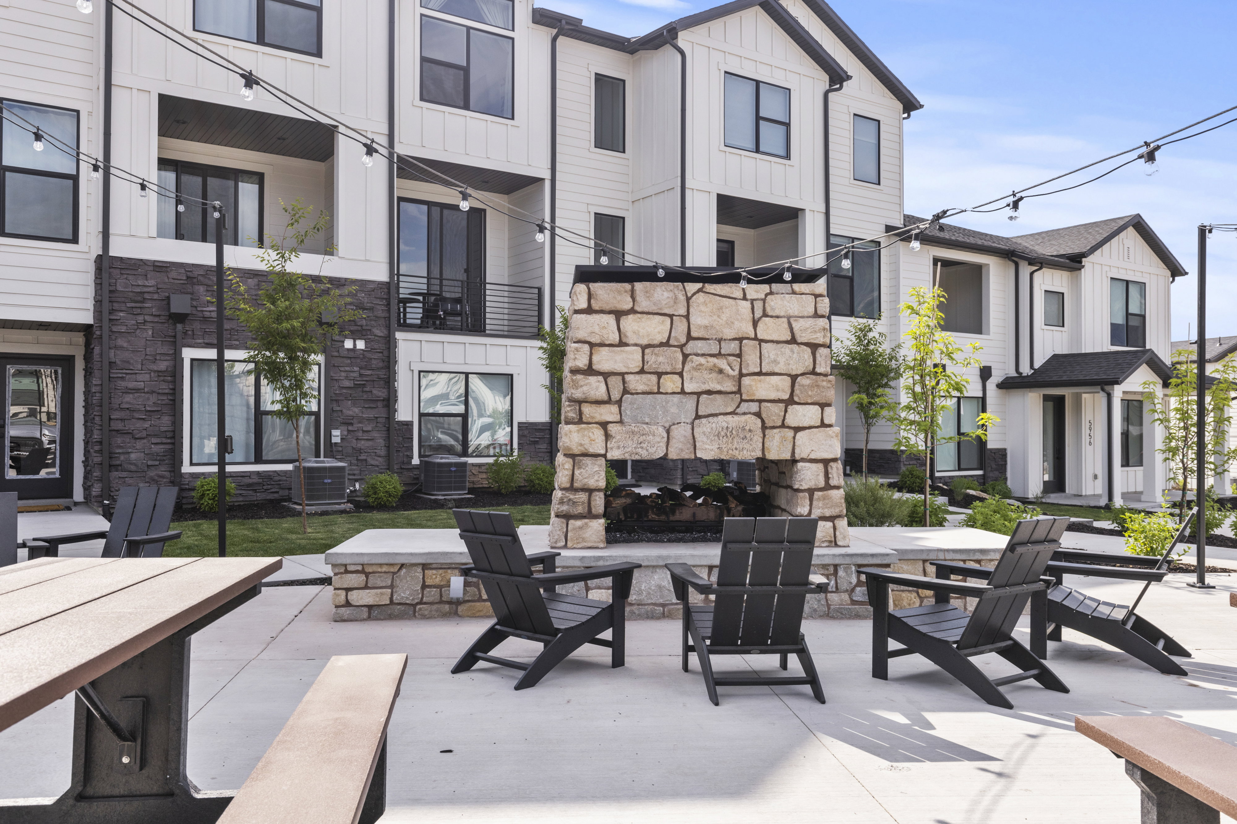 Outdoor patio featuring a stone-clad fireplace, integrated seating, and string lighting