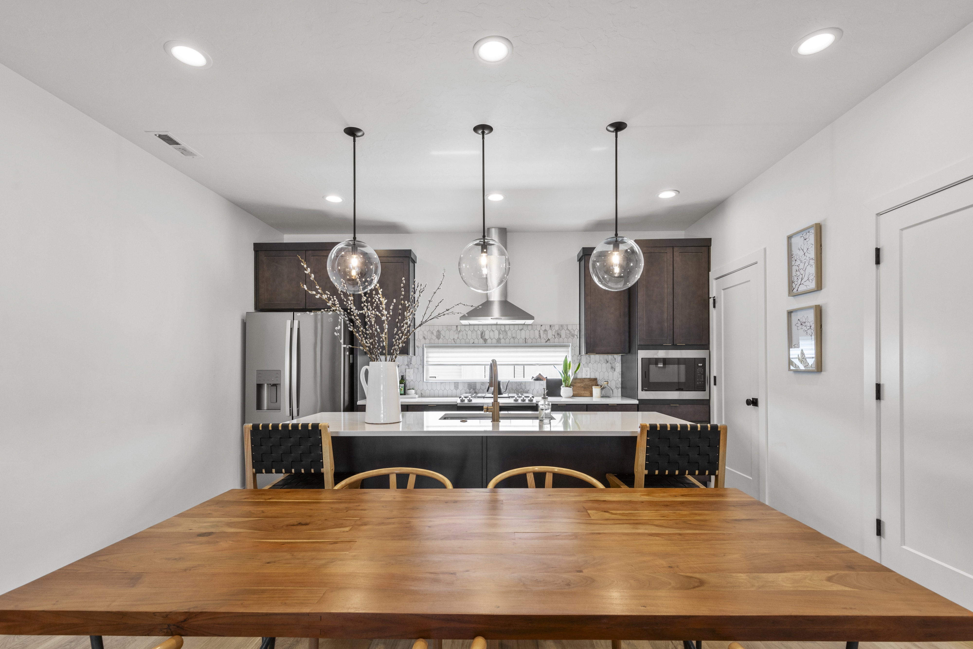 Kitchen featuring stainless steel appliances, dark wood-finish cabinetry, a white countertop island, pendant lighting, and recessed ceiling lights
